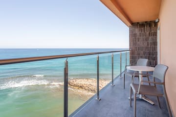 a balcony with a table and chairs overlooking the ocean