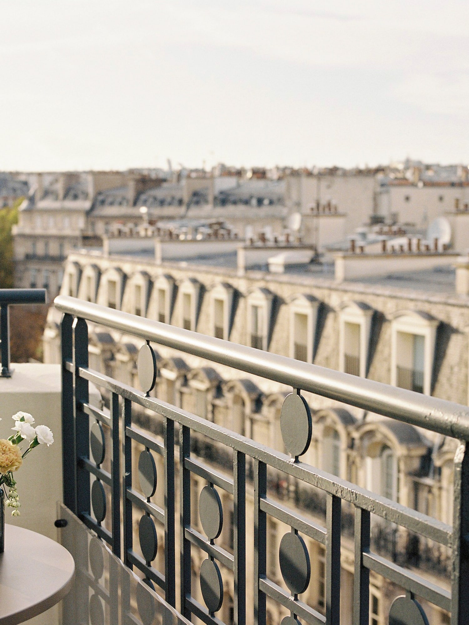a balcony with a vase of flowers and a railing