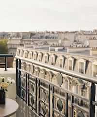 a balcony with a vase of flowers and a railing