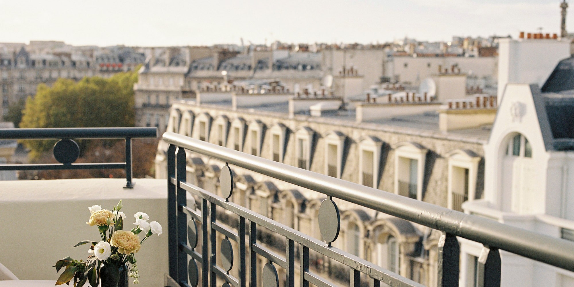 a balcony with a vase of flowers and a railing