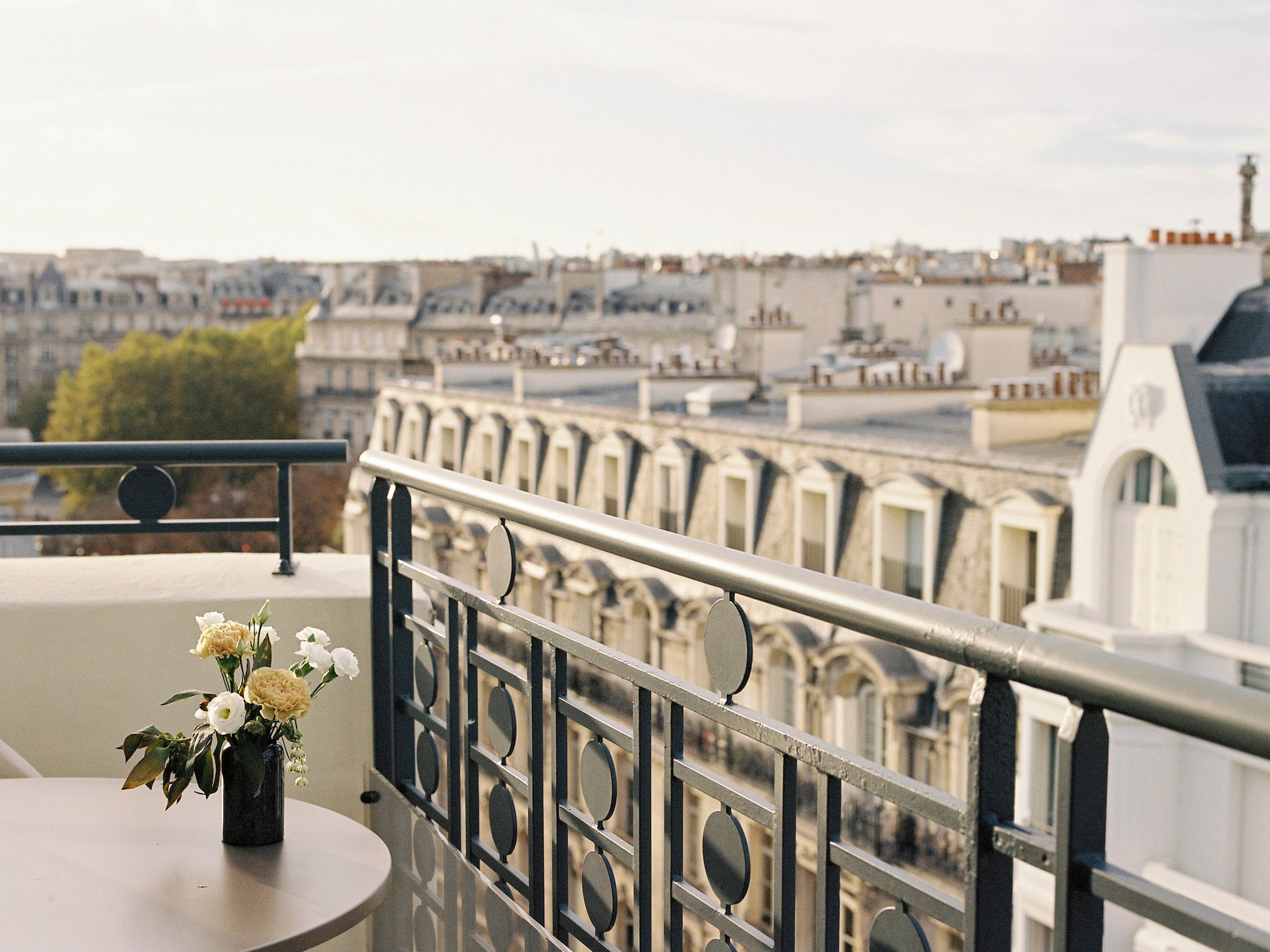 a balcony with a vase of flowers and a railing