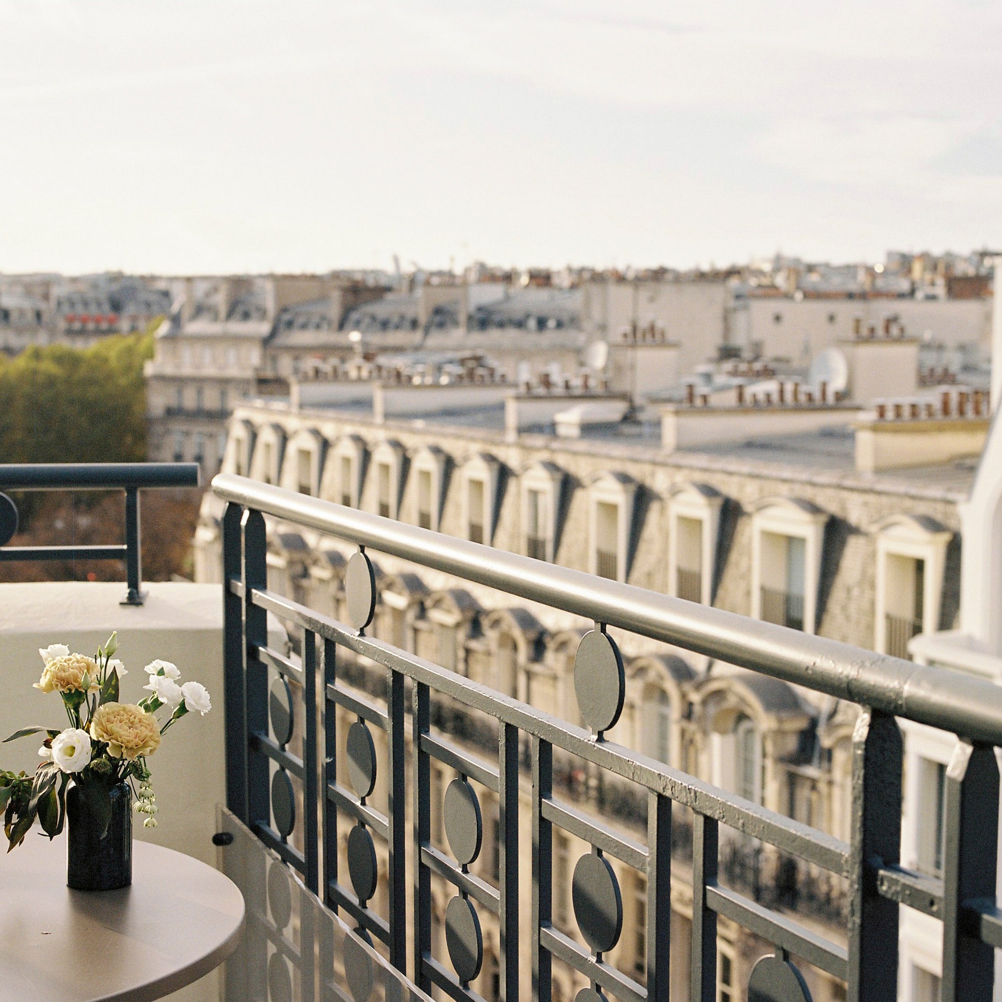 a balcony with a vase of flowers and a railing