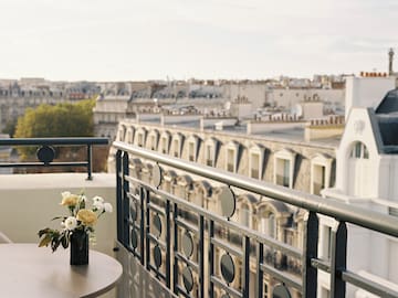 a balcony with a vase of flowers and a railing