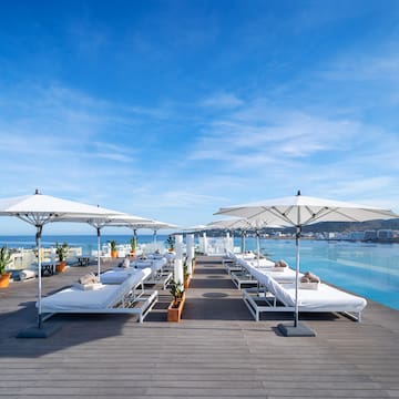 a pool with white lounge chairs and umbrellas