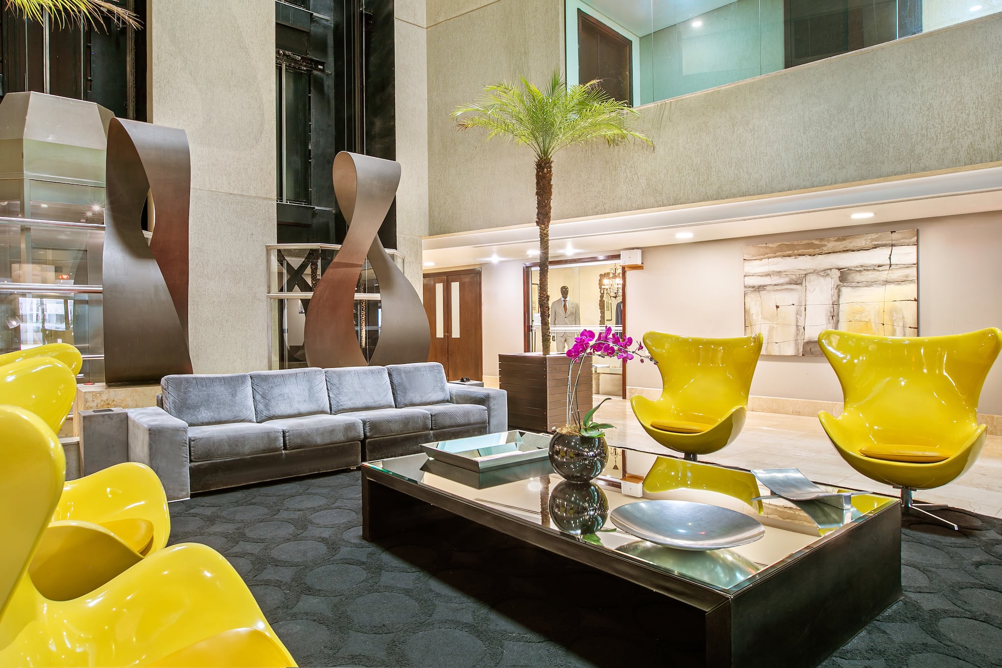 a room with a couch and a table with chairs and a palm tree