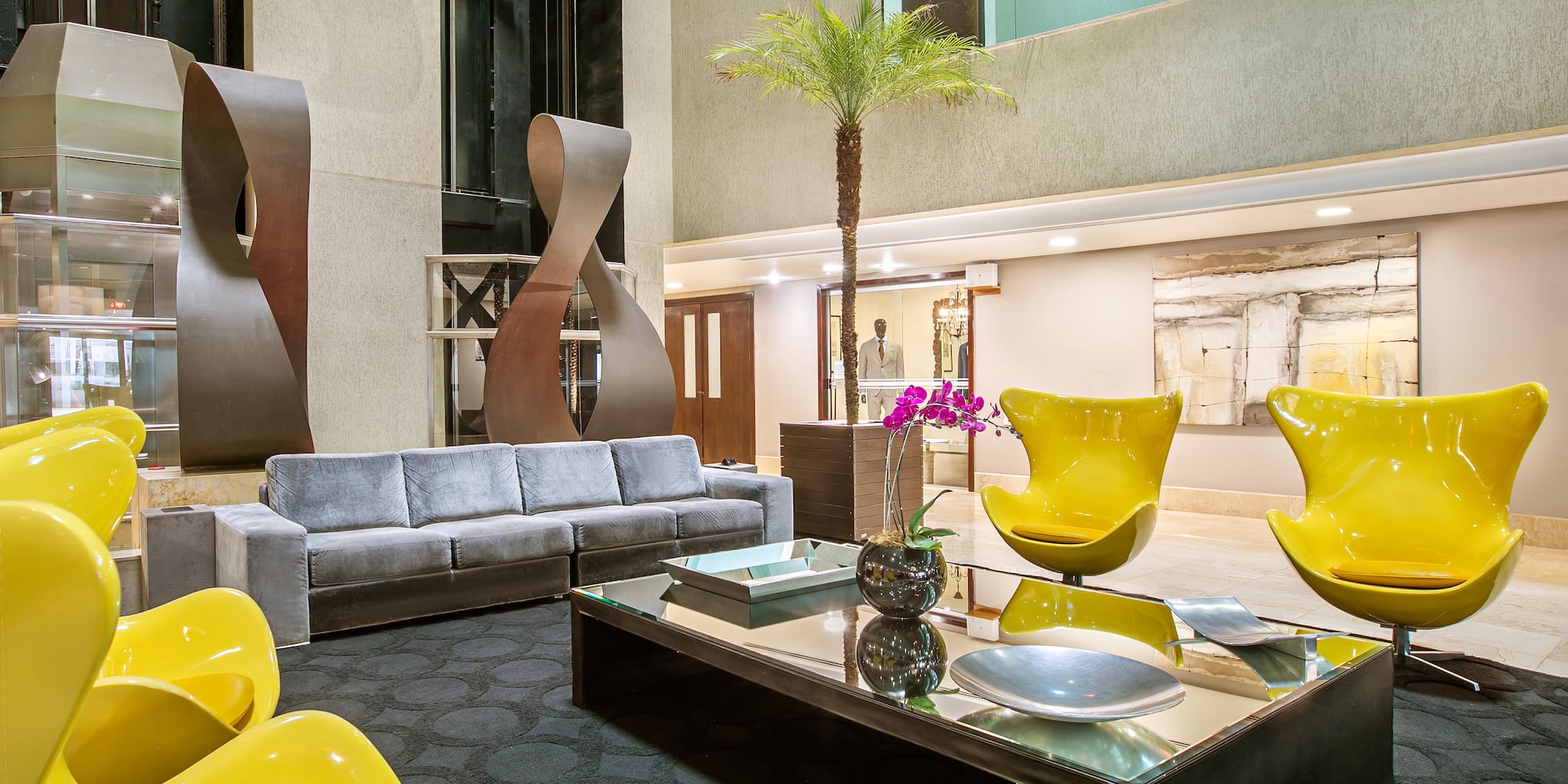 a room with a couch and a table with chairs and a palm tree