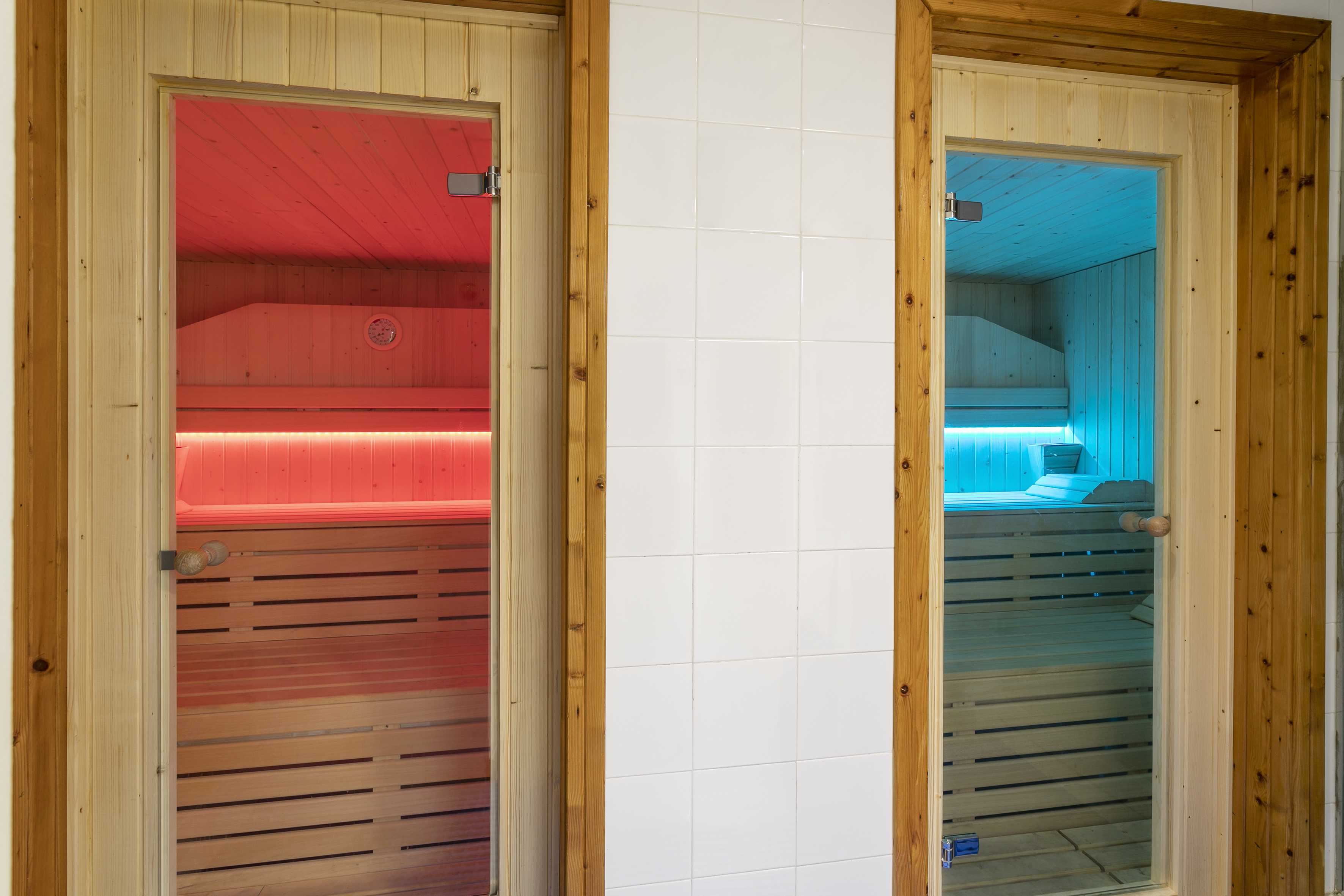 Wooden saunas with glass doors, red light therapy and blue light therapy.