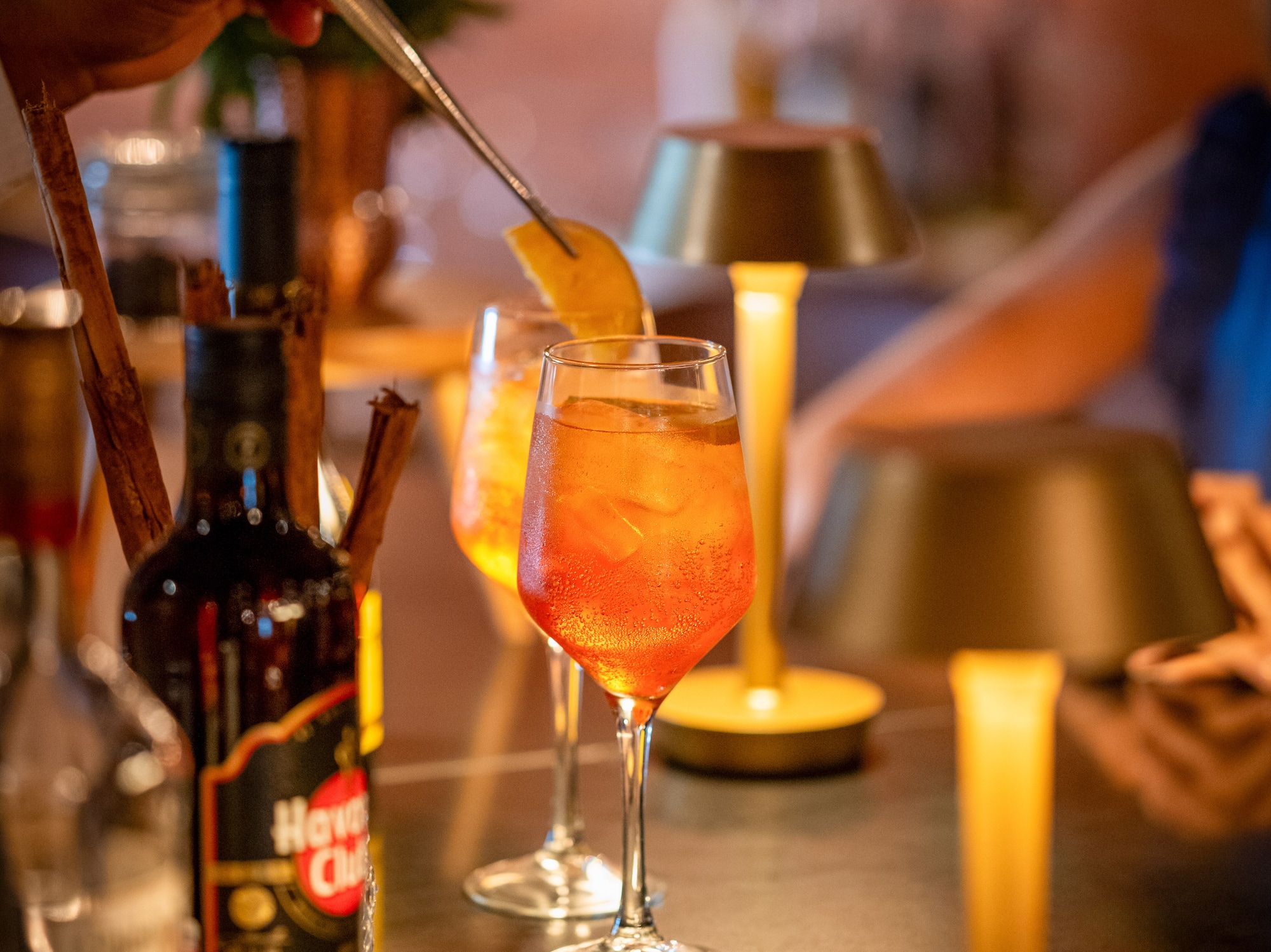 a person putting a lemon into a glass of alcohol