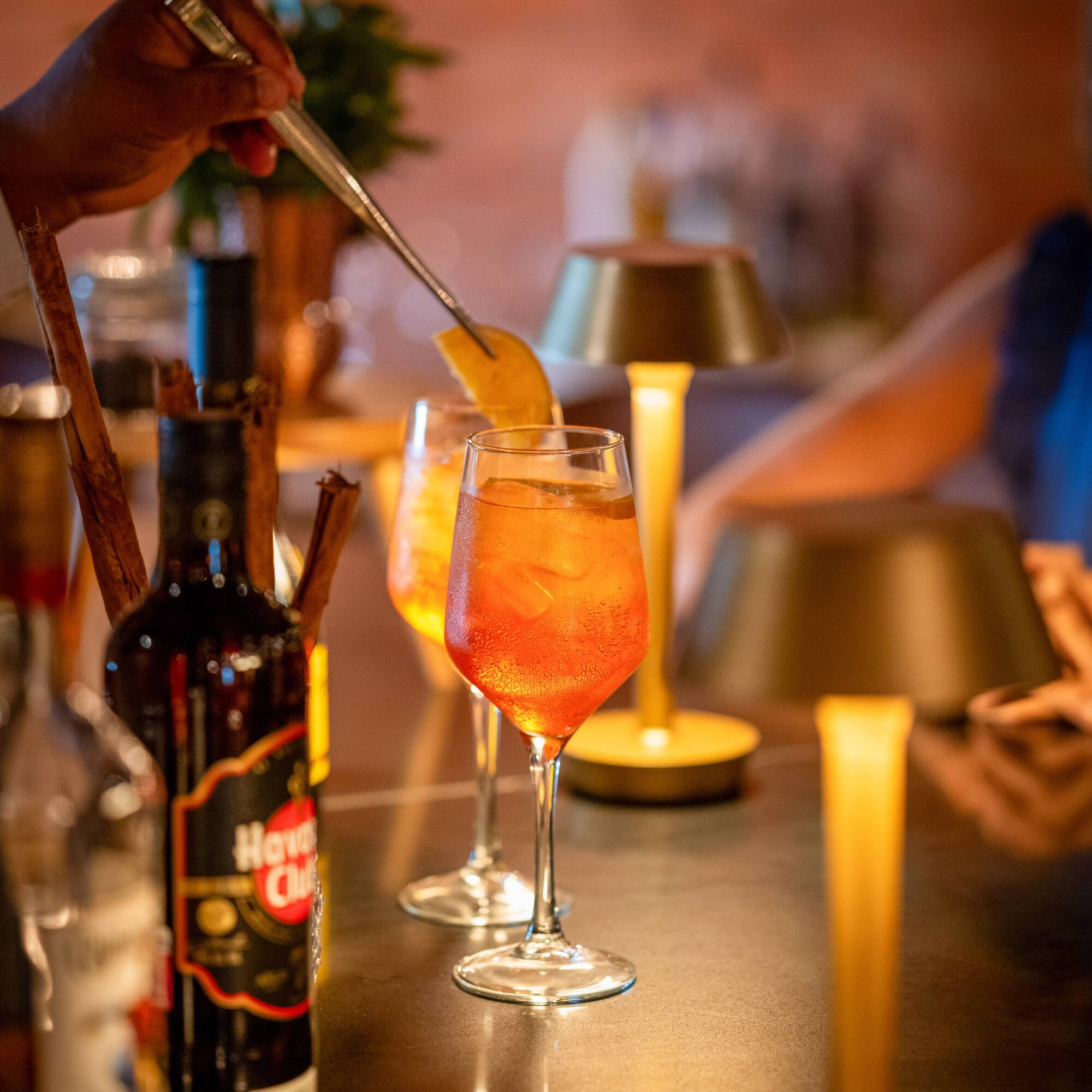 a person putting a lemon into a glass of alcohol