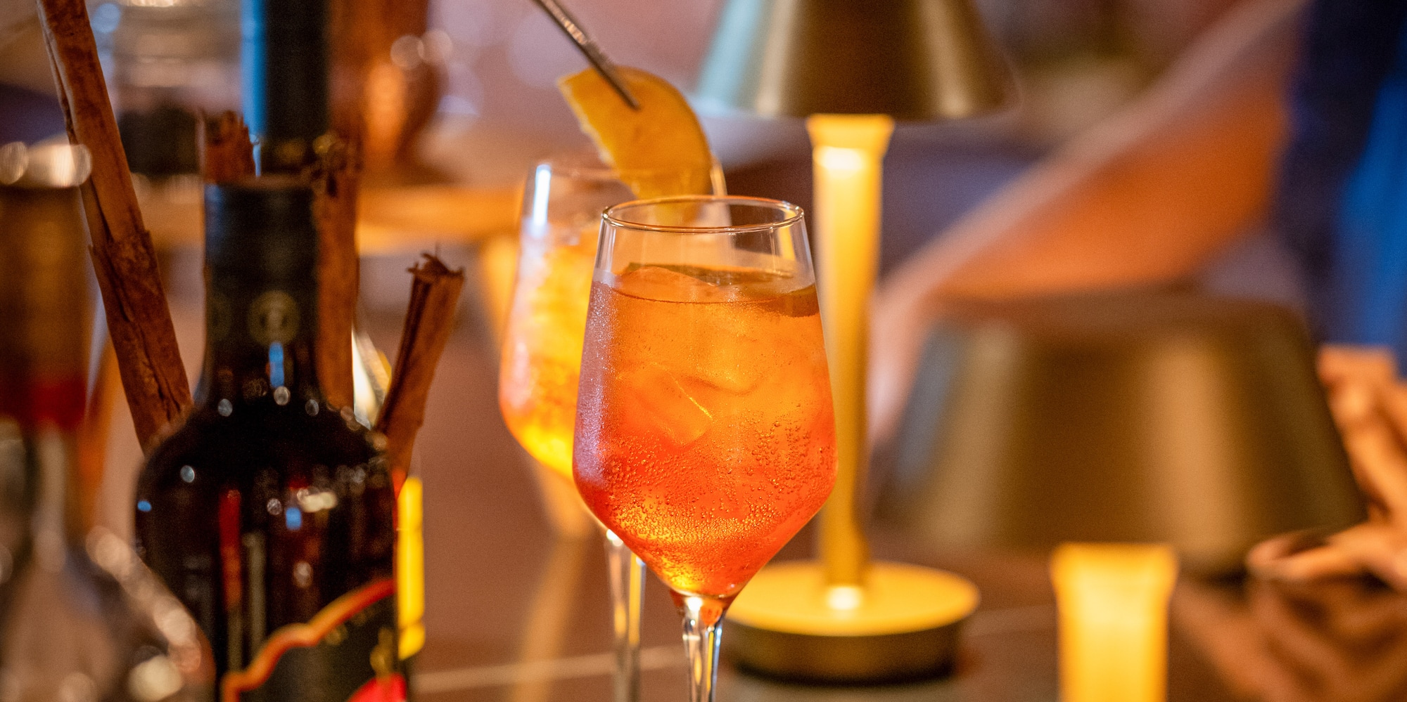 a person putting a lemon into a glass of alcohol