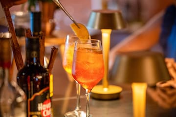 a person putting a lemon into a glass of alcohol
