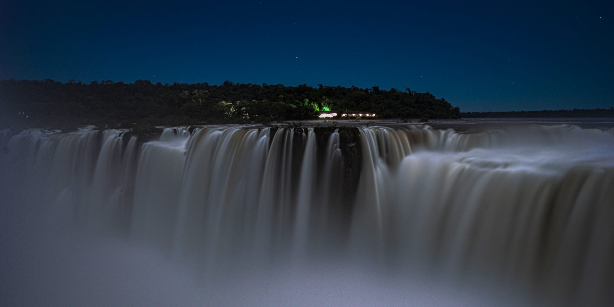 a waterfall with a forest in the background