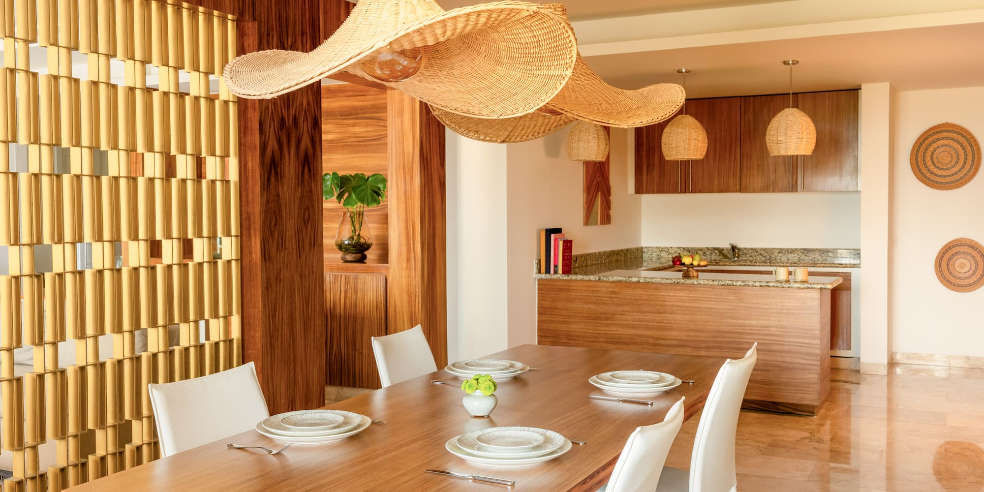 Modern open dining room with wood table, white chairs, large wicker pendant lights.