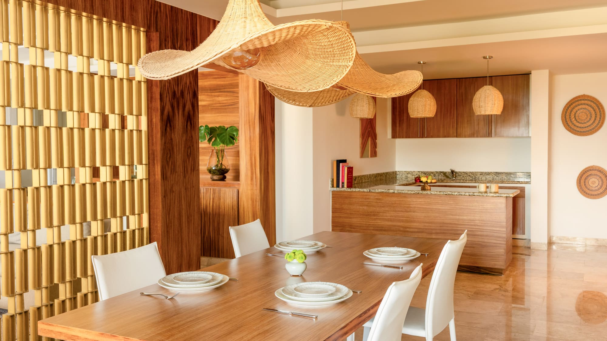 Modern open dining room with wood table, white chairs, large wicker pendant lights.