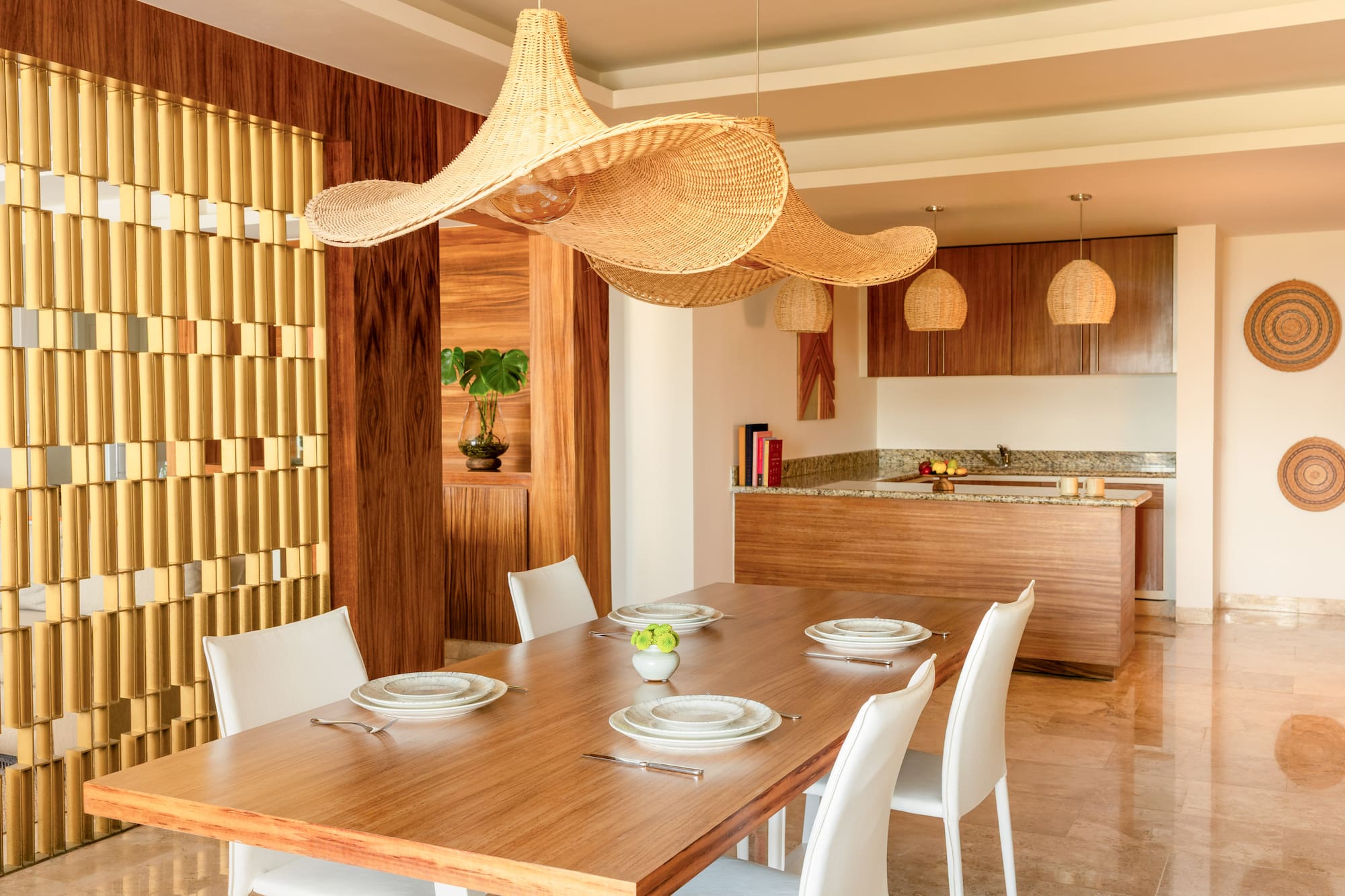 Modern open dining room with wood table, white chairs, large wicker pendant lights.