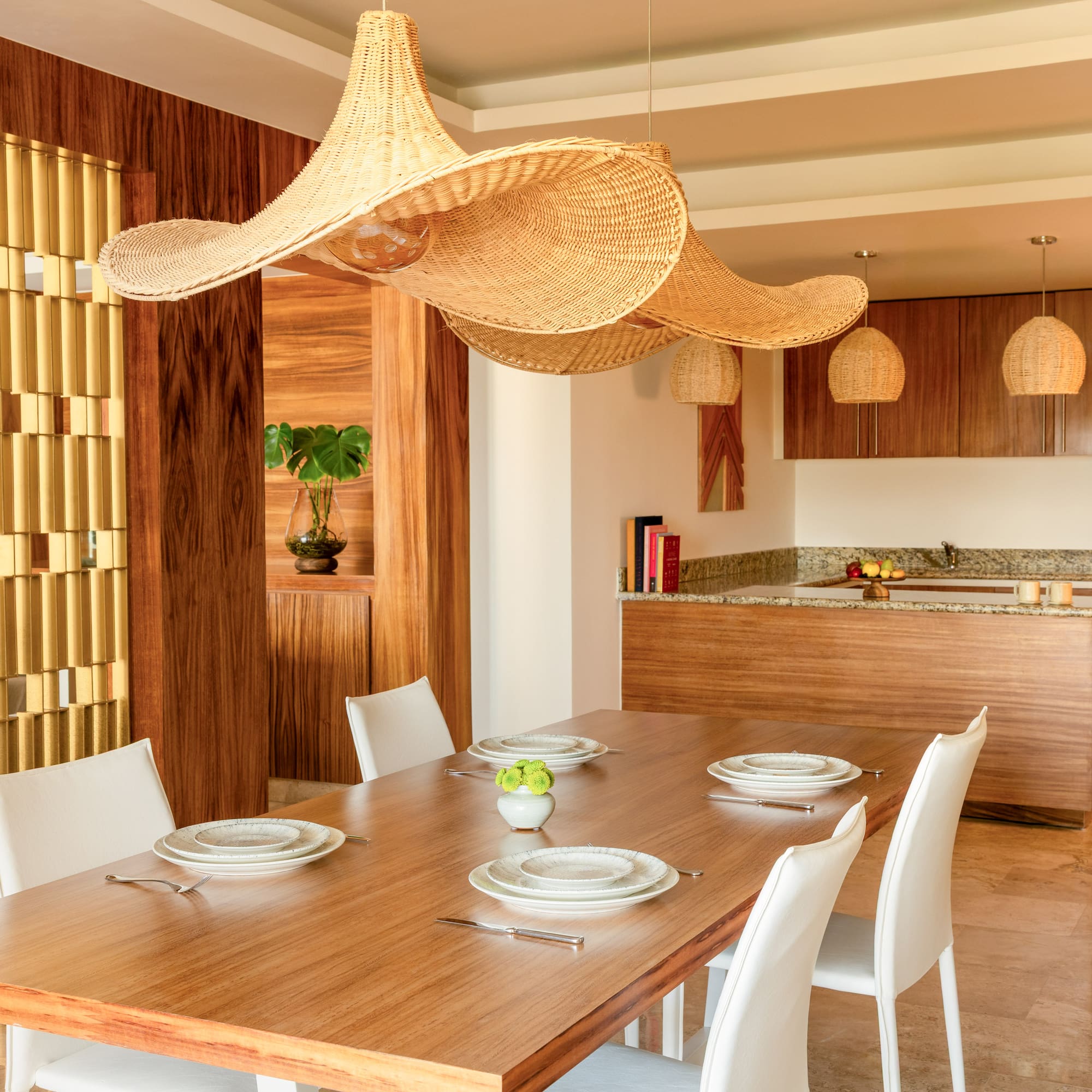 Modern open dining room with wood table, white chairs, large wicker pendant lights.