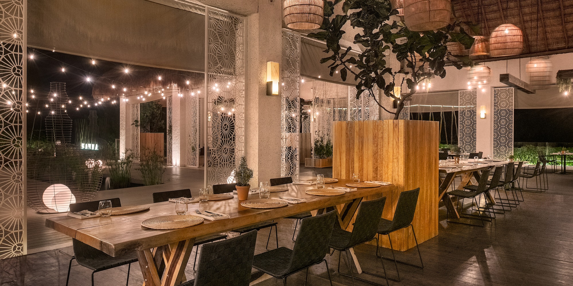 a long table with plates and chairs in a room with lights