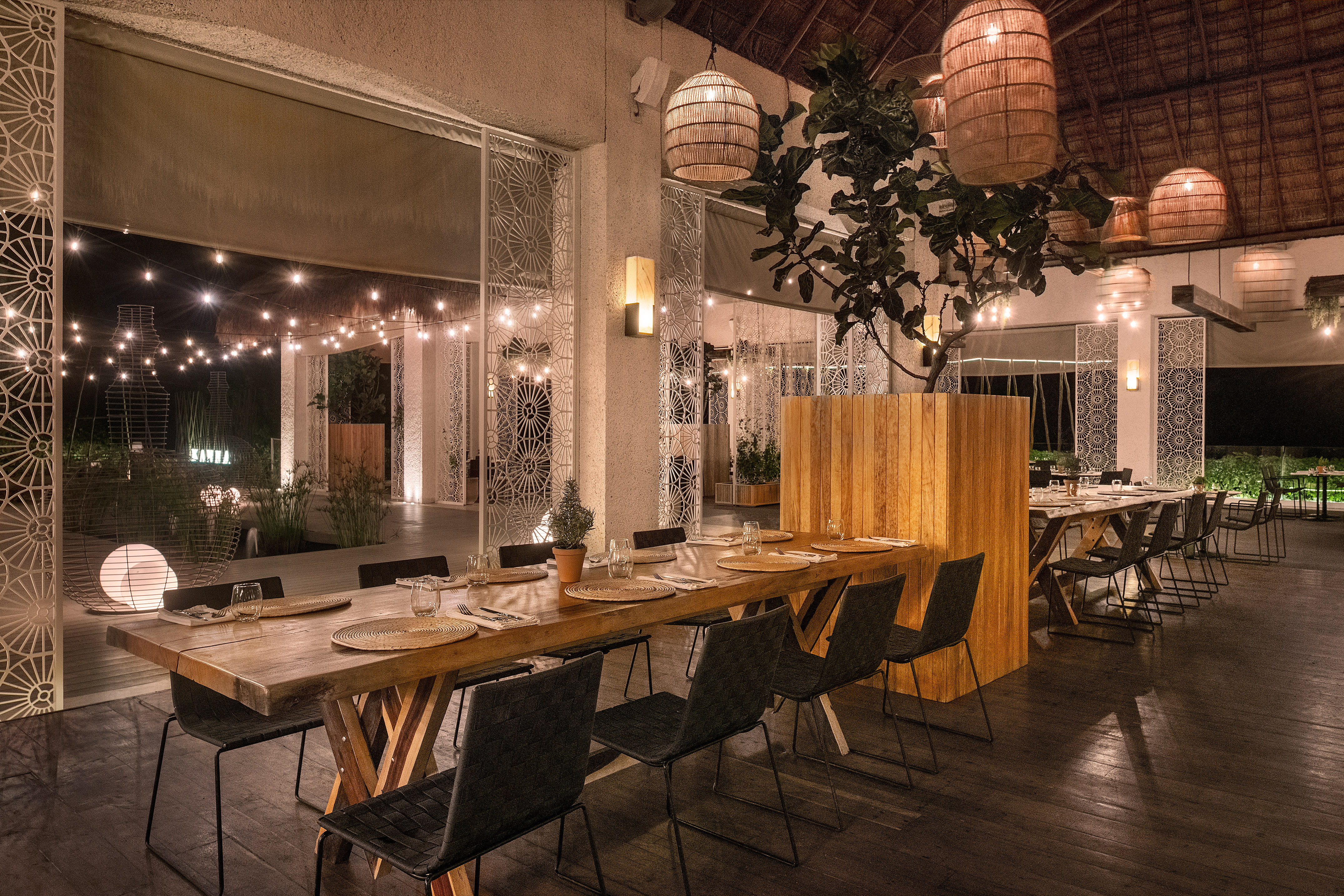Elegant tropical restaurant with wooden tables, woven lanterns, and string lights.