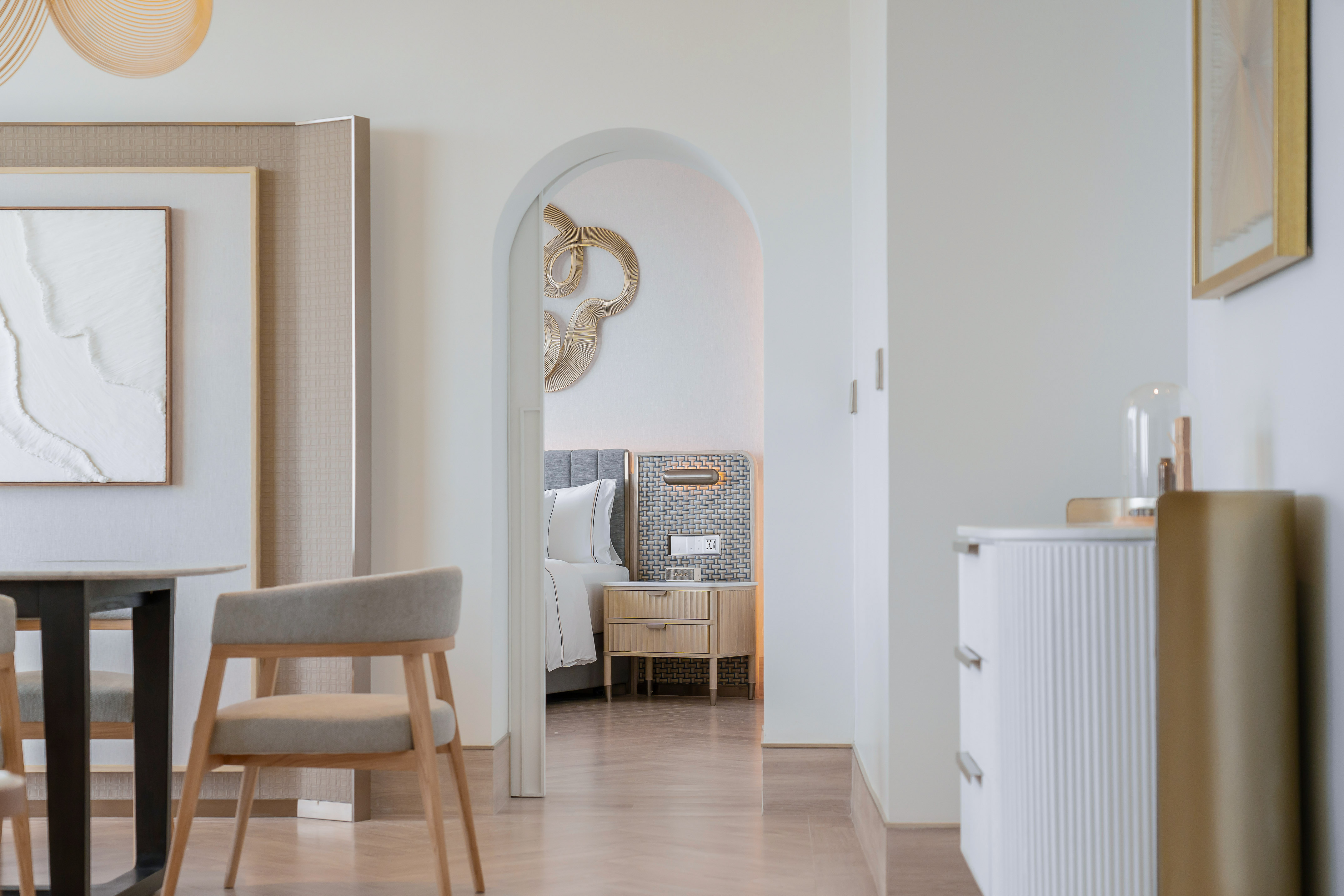 Modern luxury hotel room with living area and arched bedroom entrance.