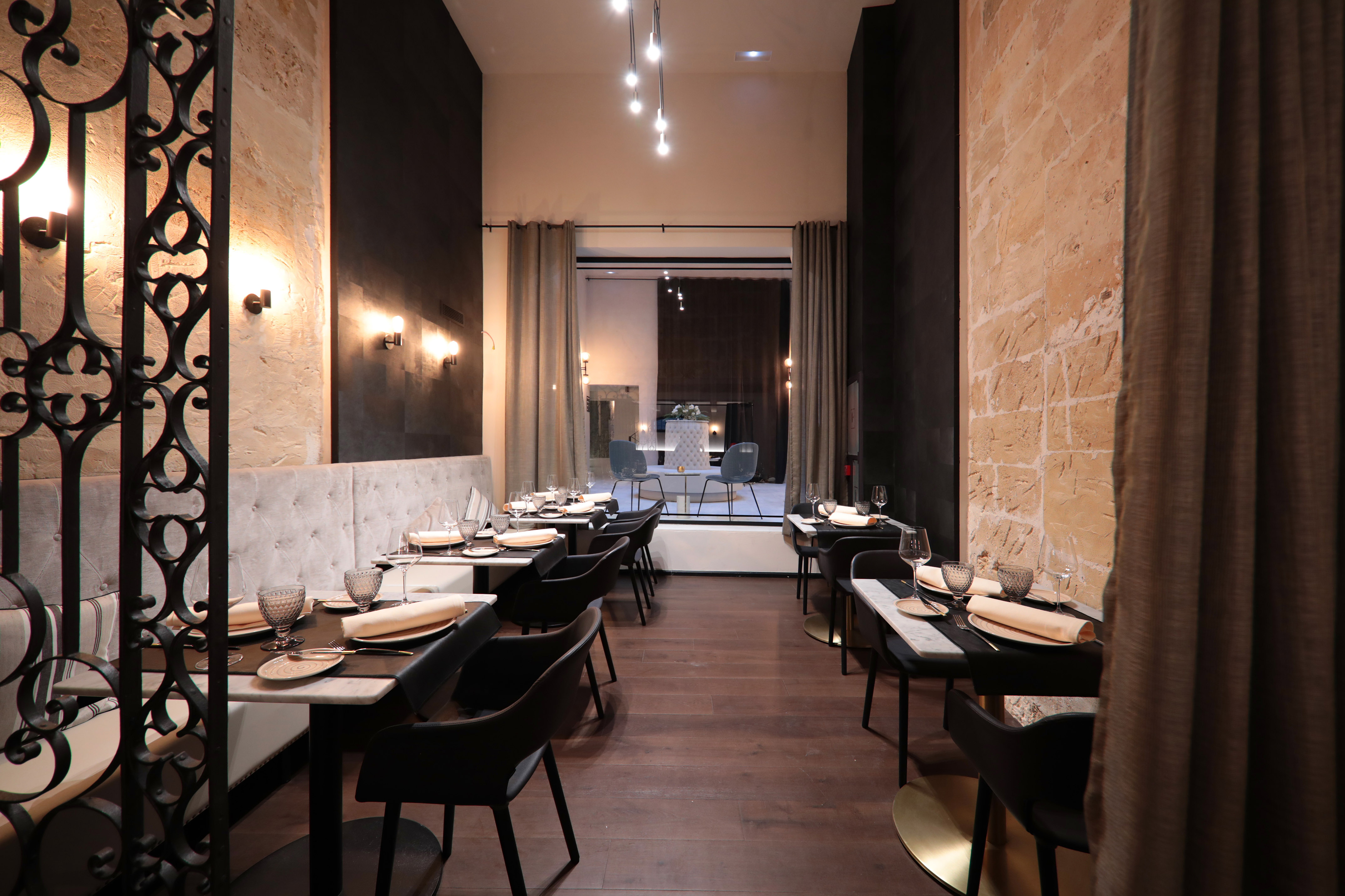 Elegant restaurant dining room with set tables, stone walls, and modern lighting.