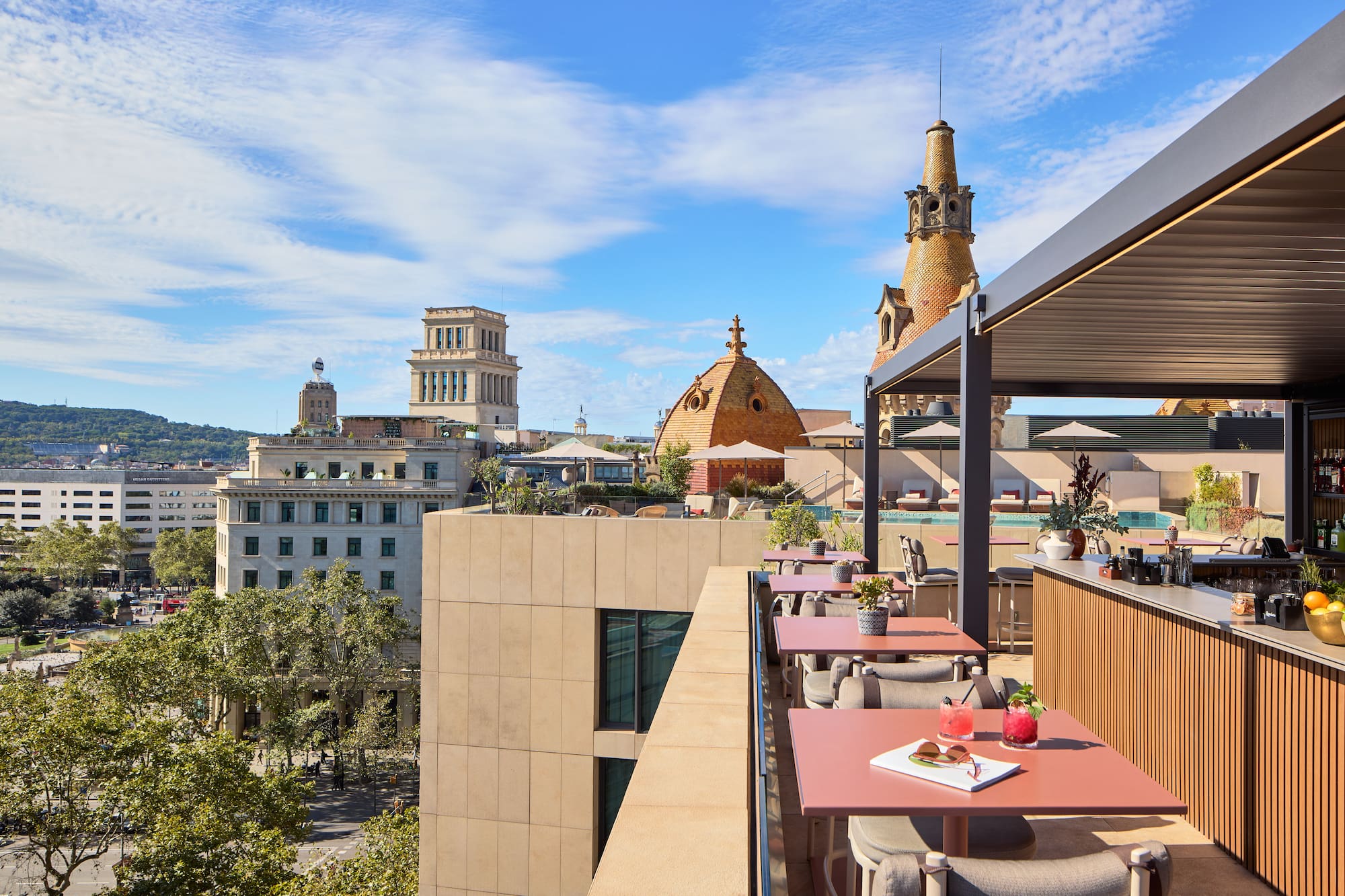 Terraza de hotel en Barcelona con bar, cócteles, piscina y vistas a la ciudad.