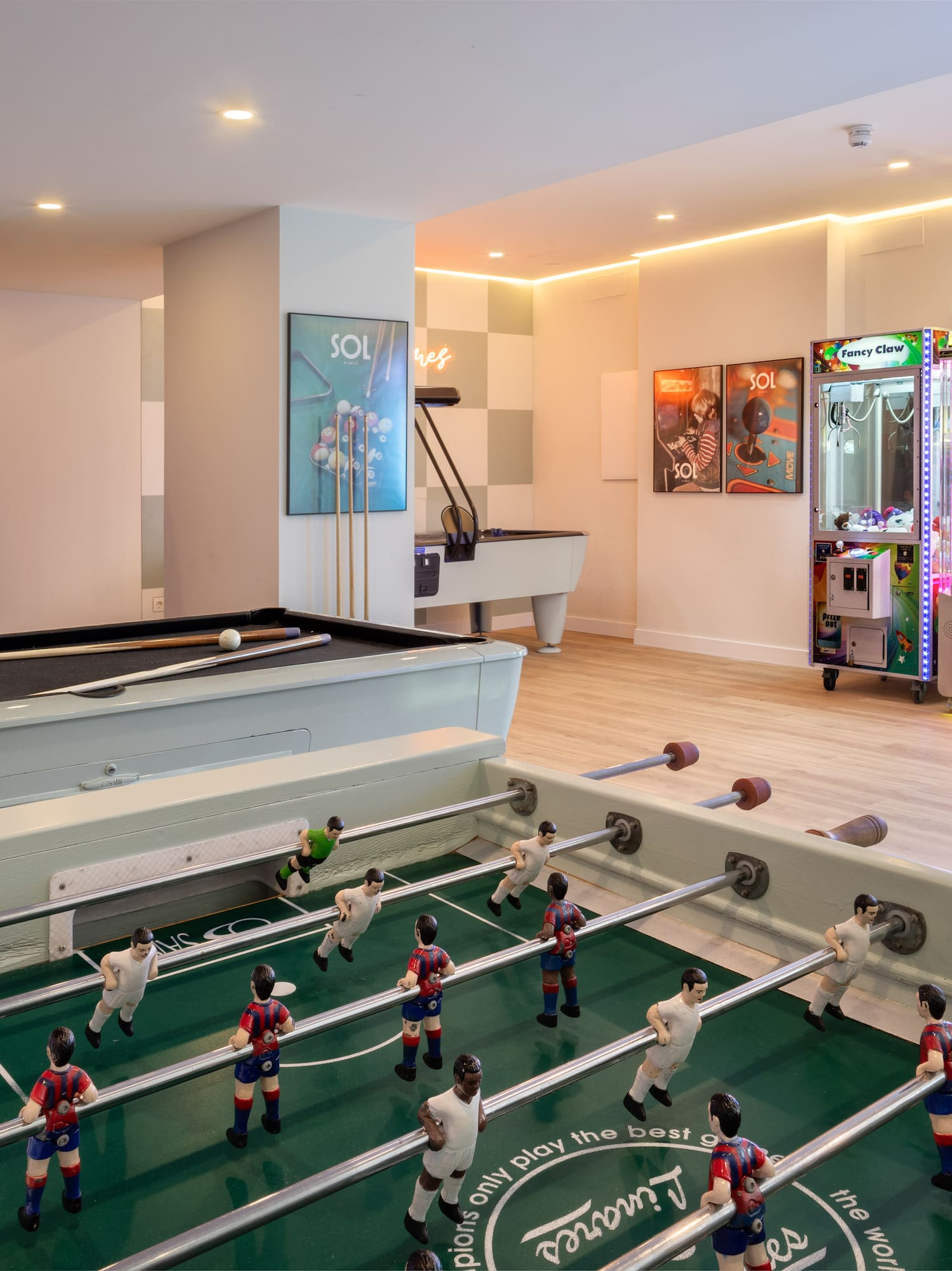 Sala de juegos con billar, futbolín y máquinas arcade populares.