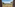 Safari lodge balcony view over sprawling African savanna, scattered trees, and hills.