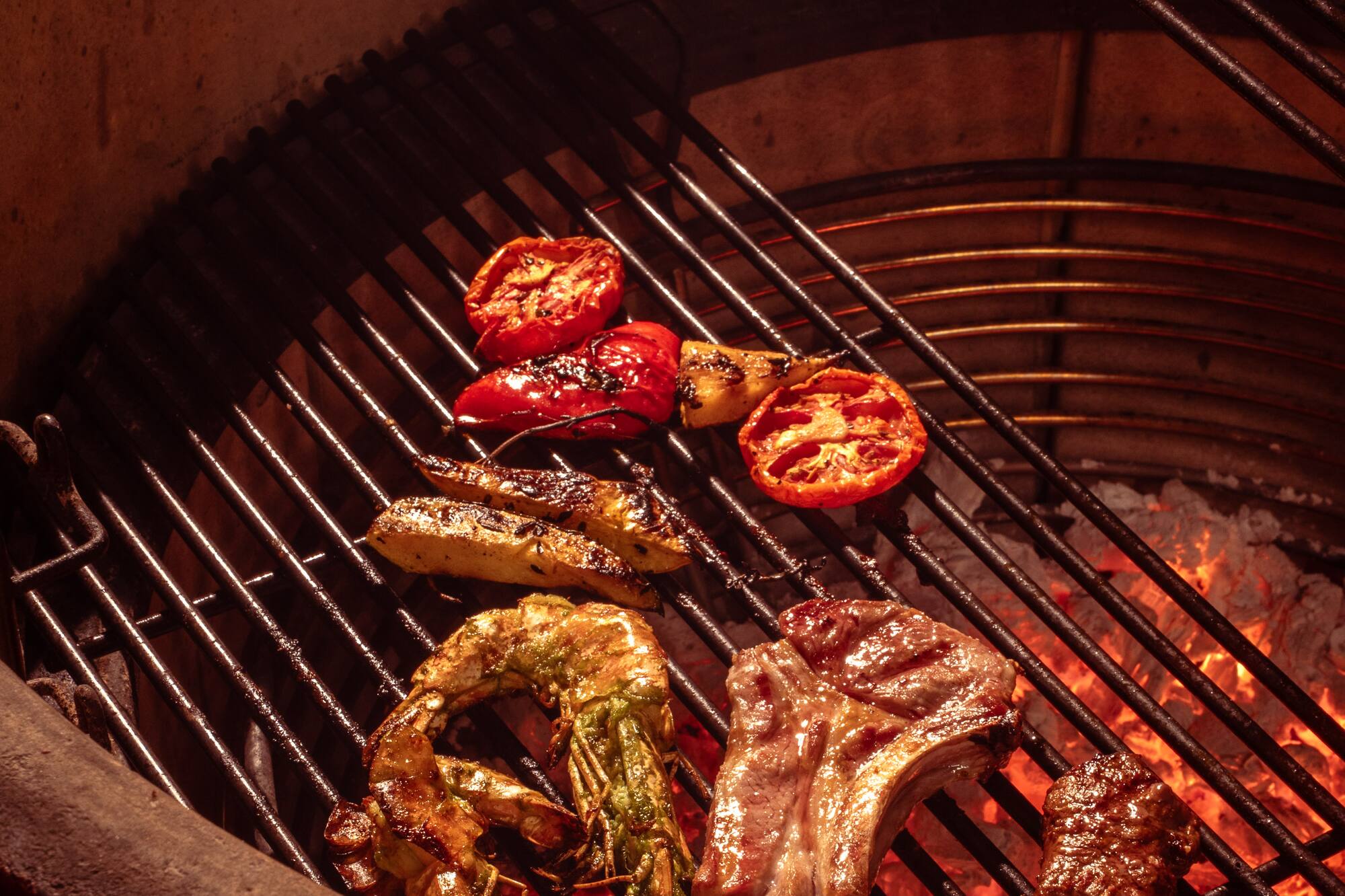 Grilling shrimp, lamb chops, tomatoes, and vegetables on a hot kamado BBQ.