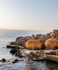 a beach with chairs and umbrellas by the water