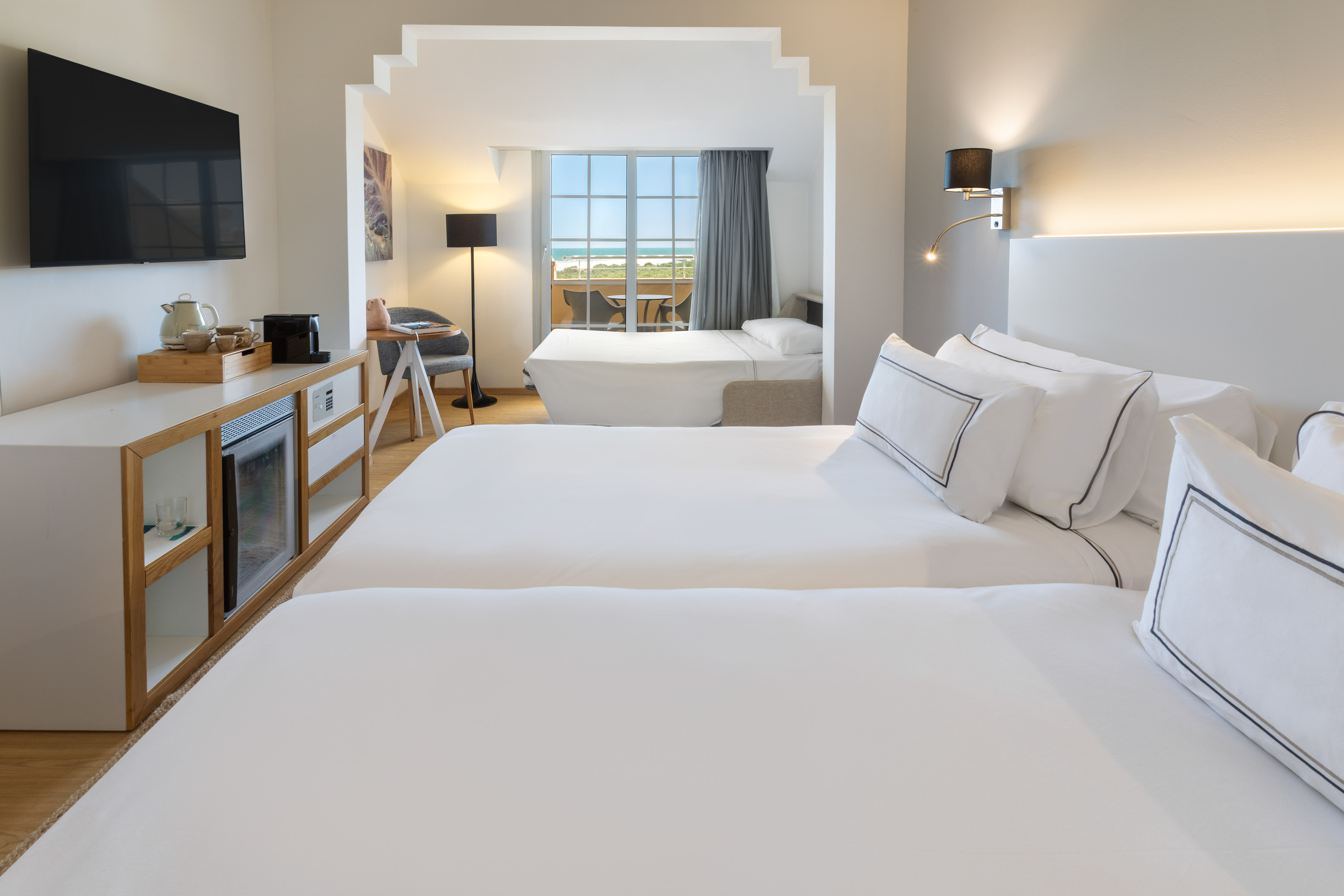 Habitación de hotel moderna con dos camas y balcón con vista al mar.