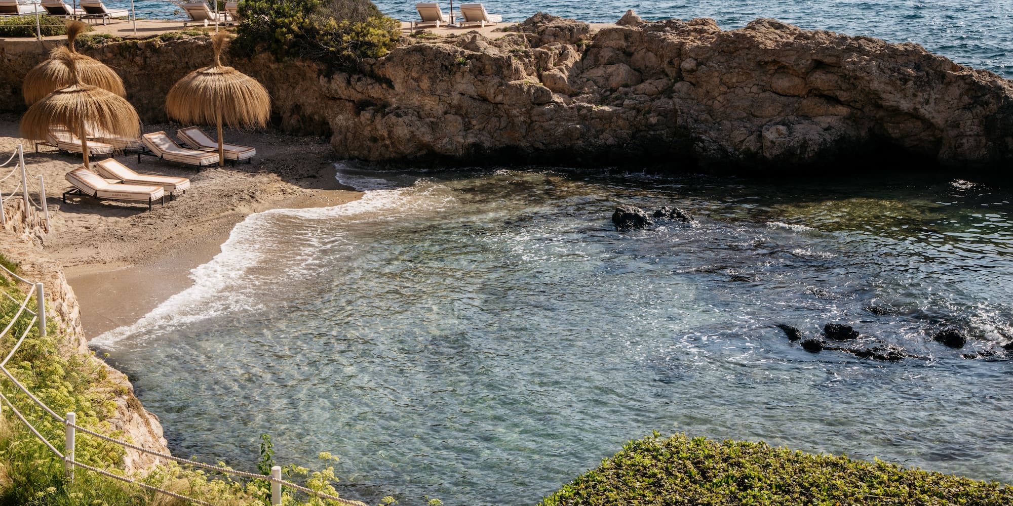 a beach with umbrellas and chairs on a rocky shore