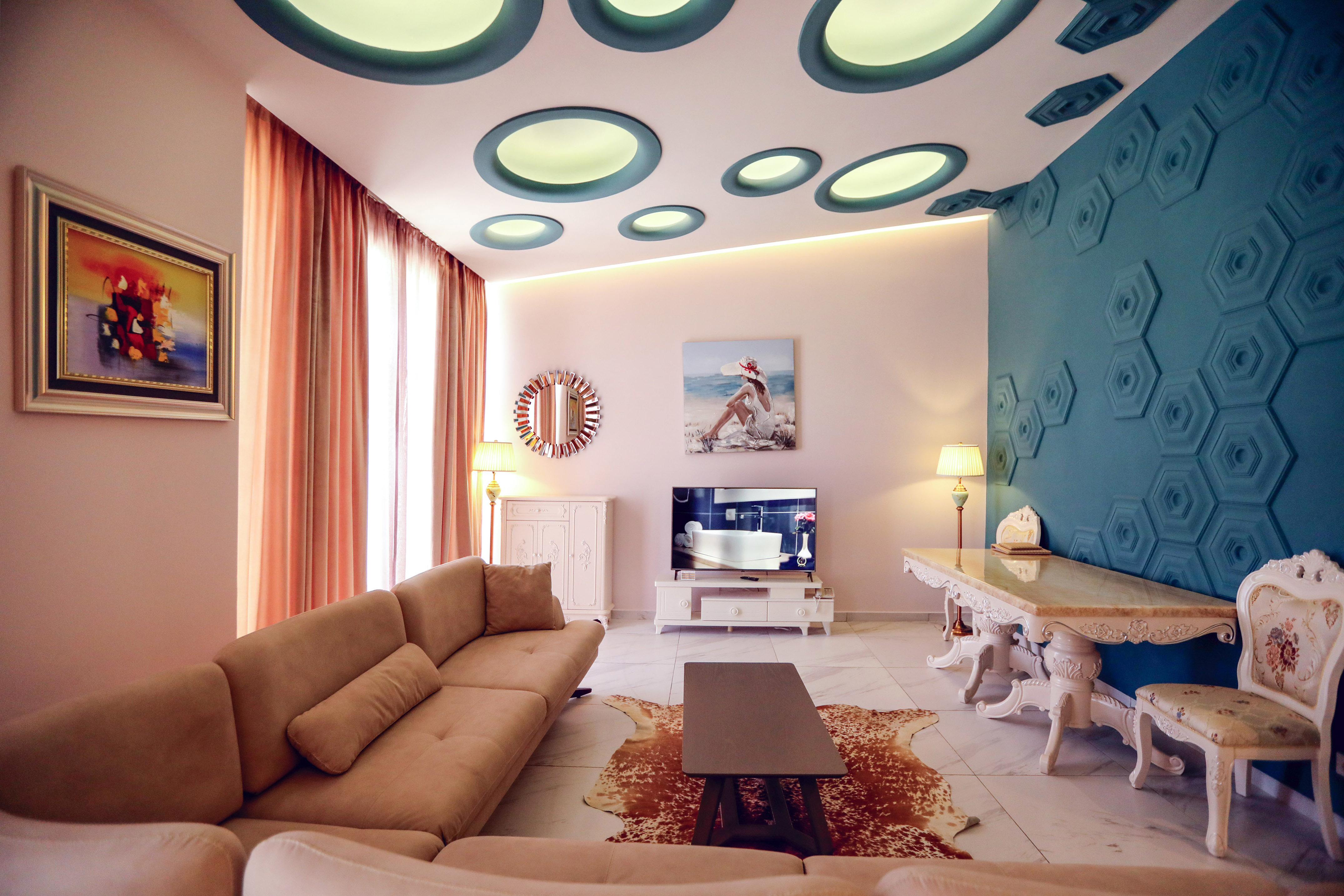 Stylish living room interior with beige sofa, teal accent wall, and unique ceiling.