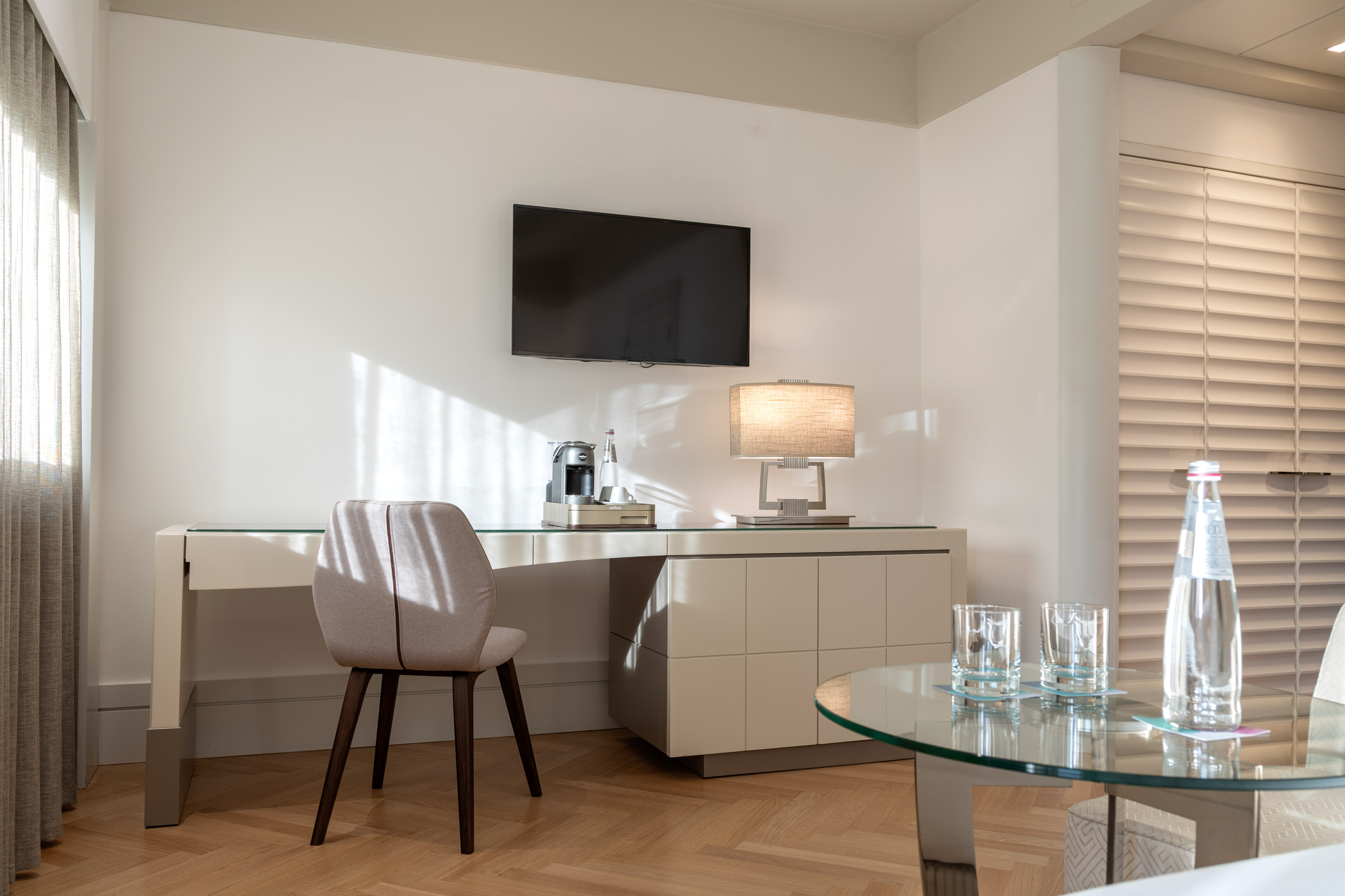Modern hotel suite featuring a workstation, TV, and coffee machine.