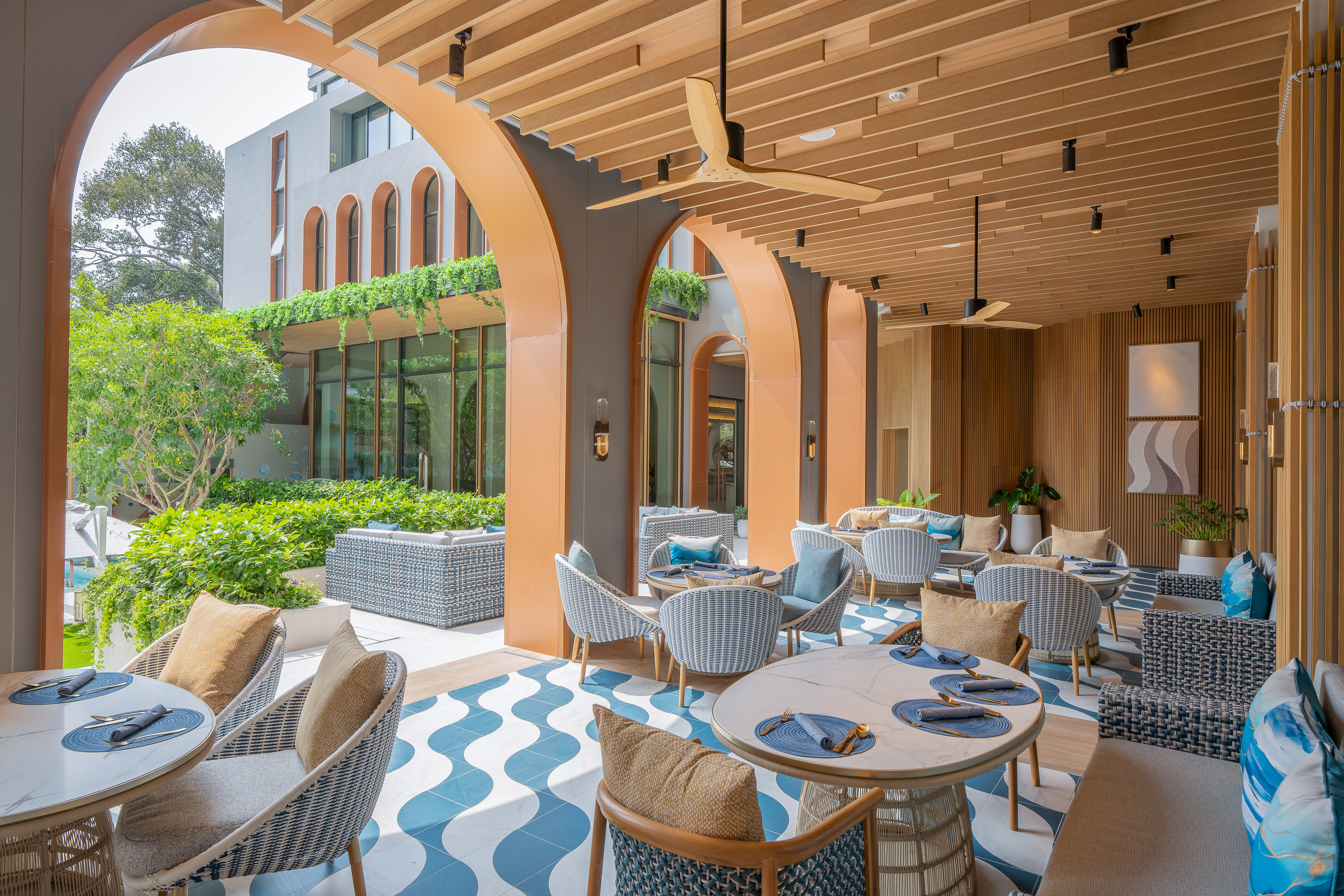 Modern tropical resort outdoor lounge with blue patterned floor and greenery. - Sanehh Sarae, Ẩm thực Quốc tế - Meliá Pattaya Hotel, Pattaya