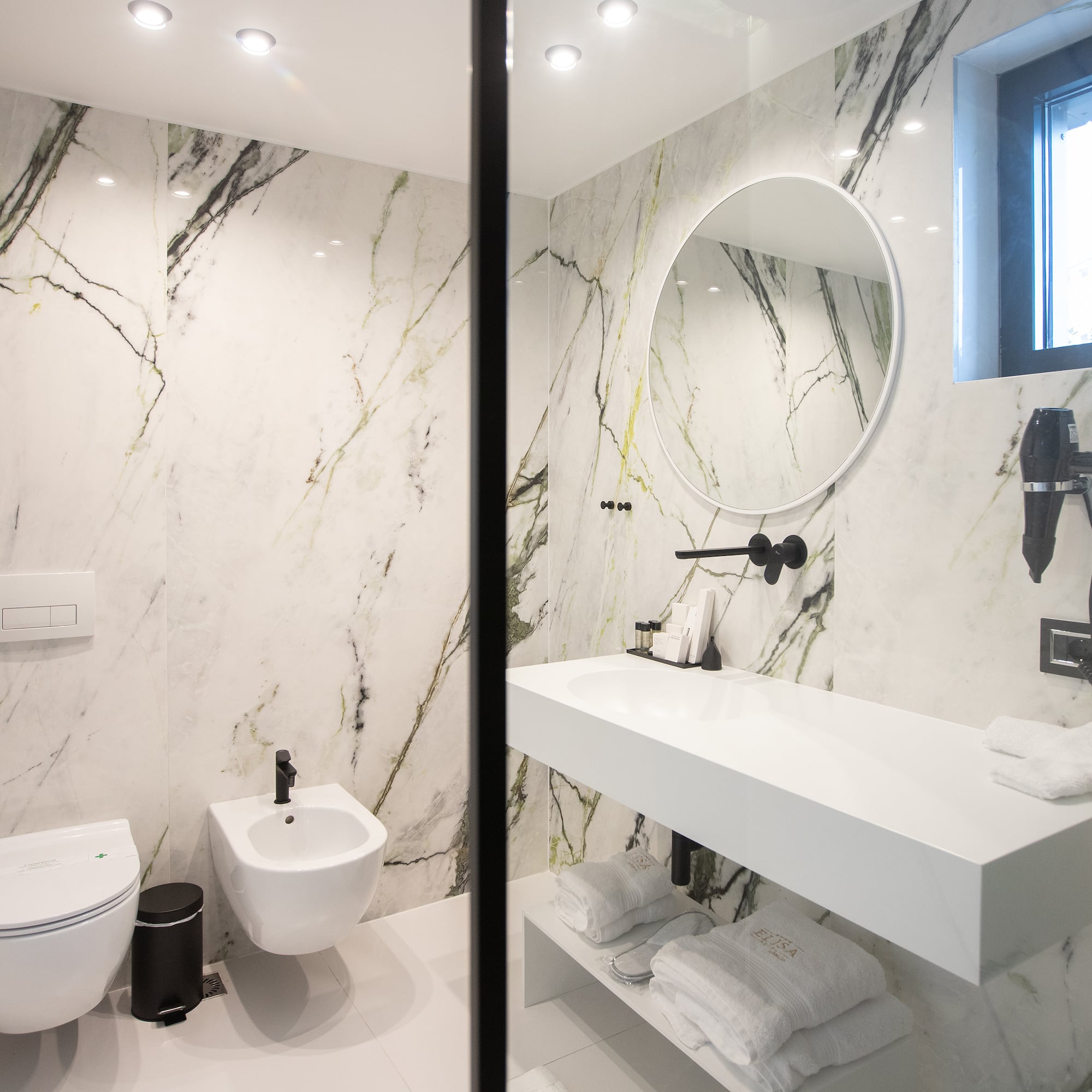 a bathroom with marble walls and a sink and toilet
