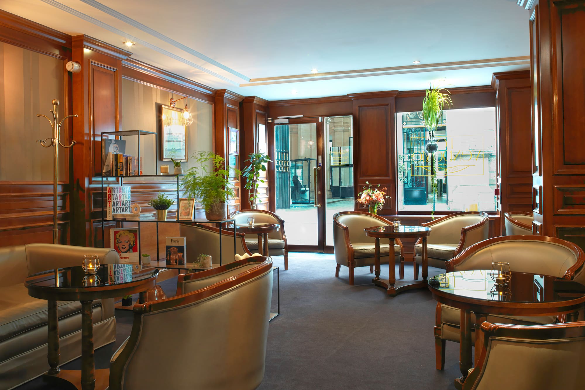 Elegant hotel lobby lounge with comfortable armchairs, round tables, and warm wood paneling.