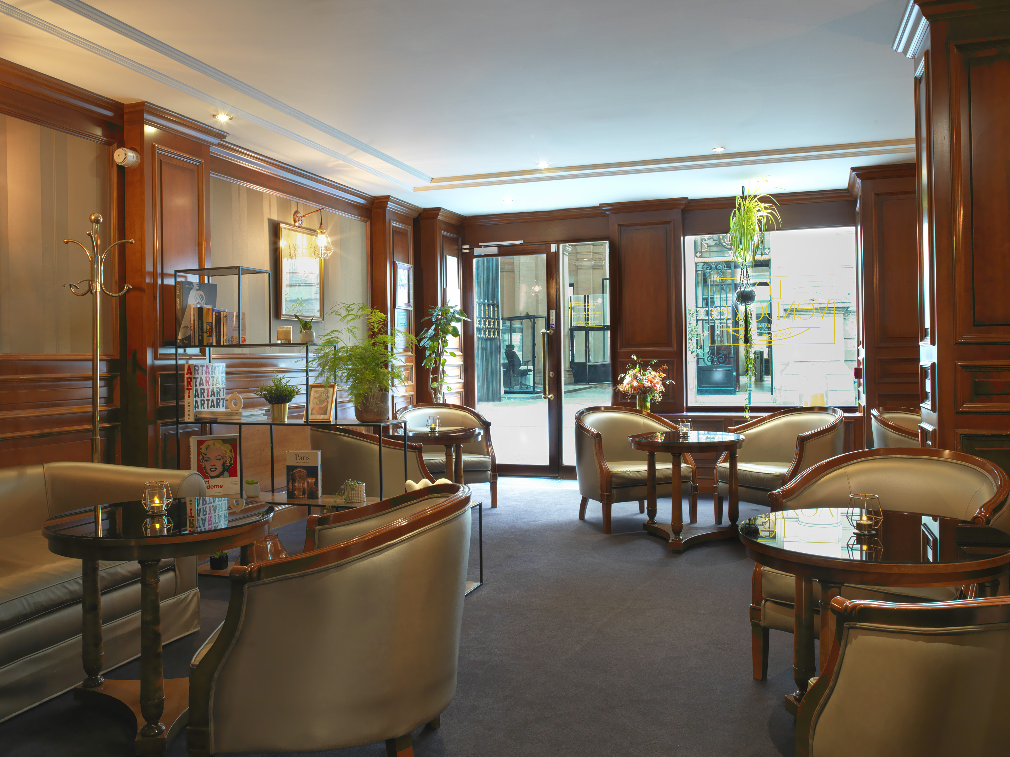 Elegant hotel lobby lounge with comfortable armchairs, round tables, and warm wood paneling.