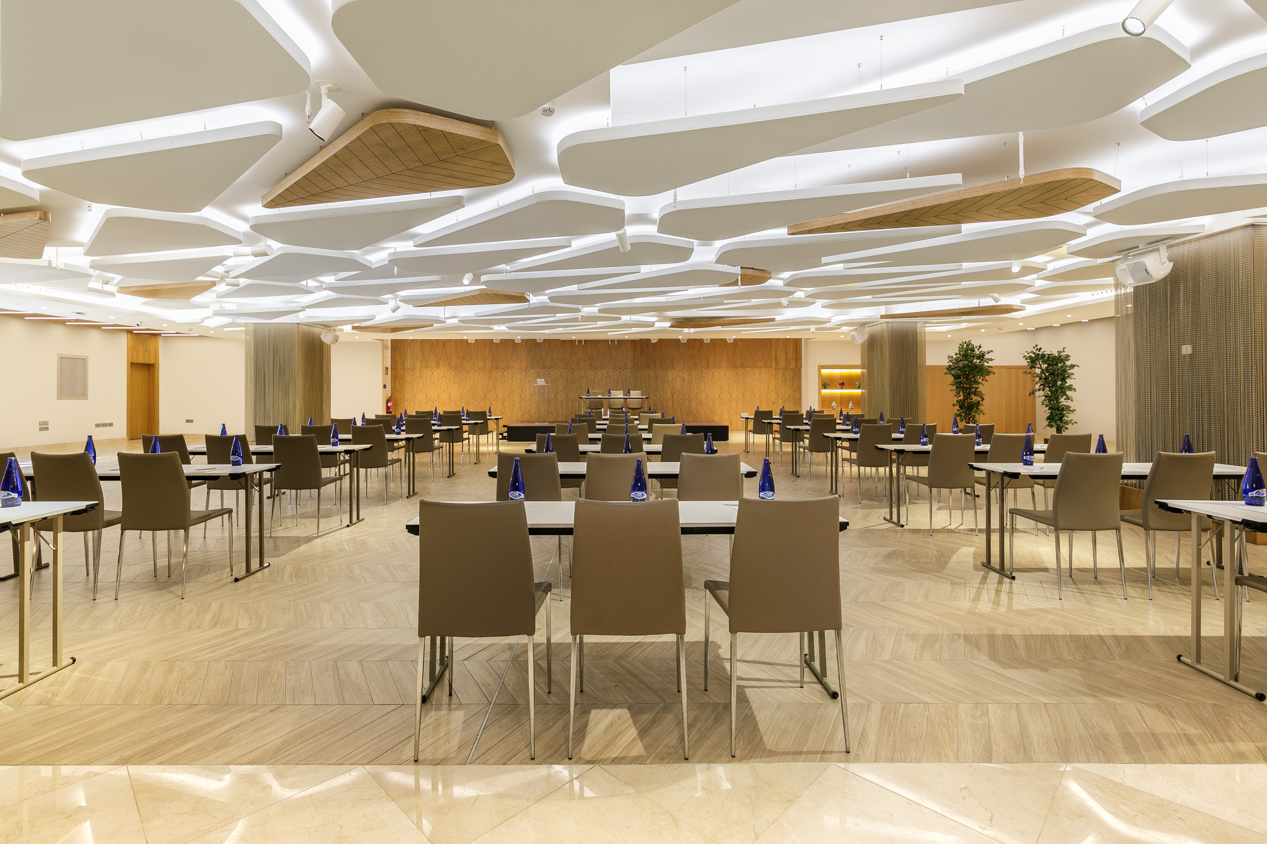 Modern conference room with tables, chairs, and stylish acoustic ceiling.