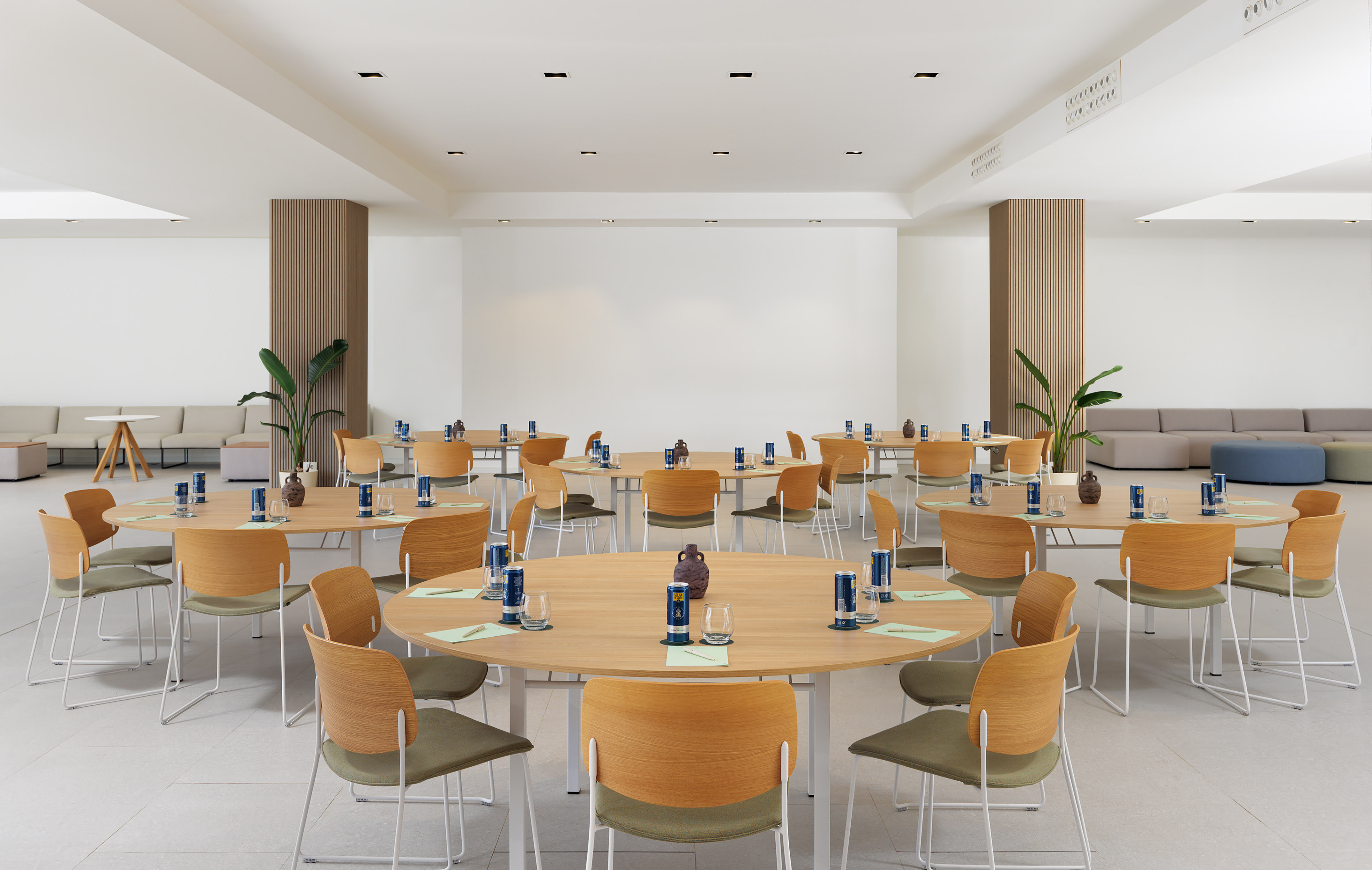 Modern conference room setup with round tables, green chairs, and lounge area.