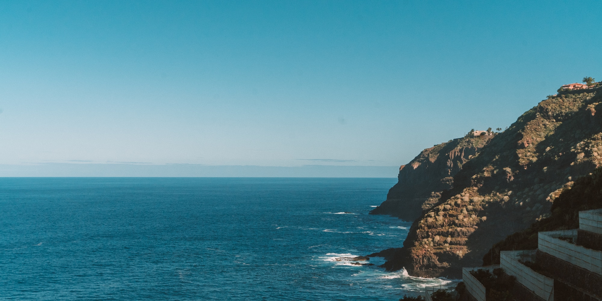 a cliff with a body of water and buildings