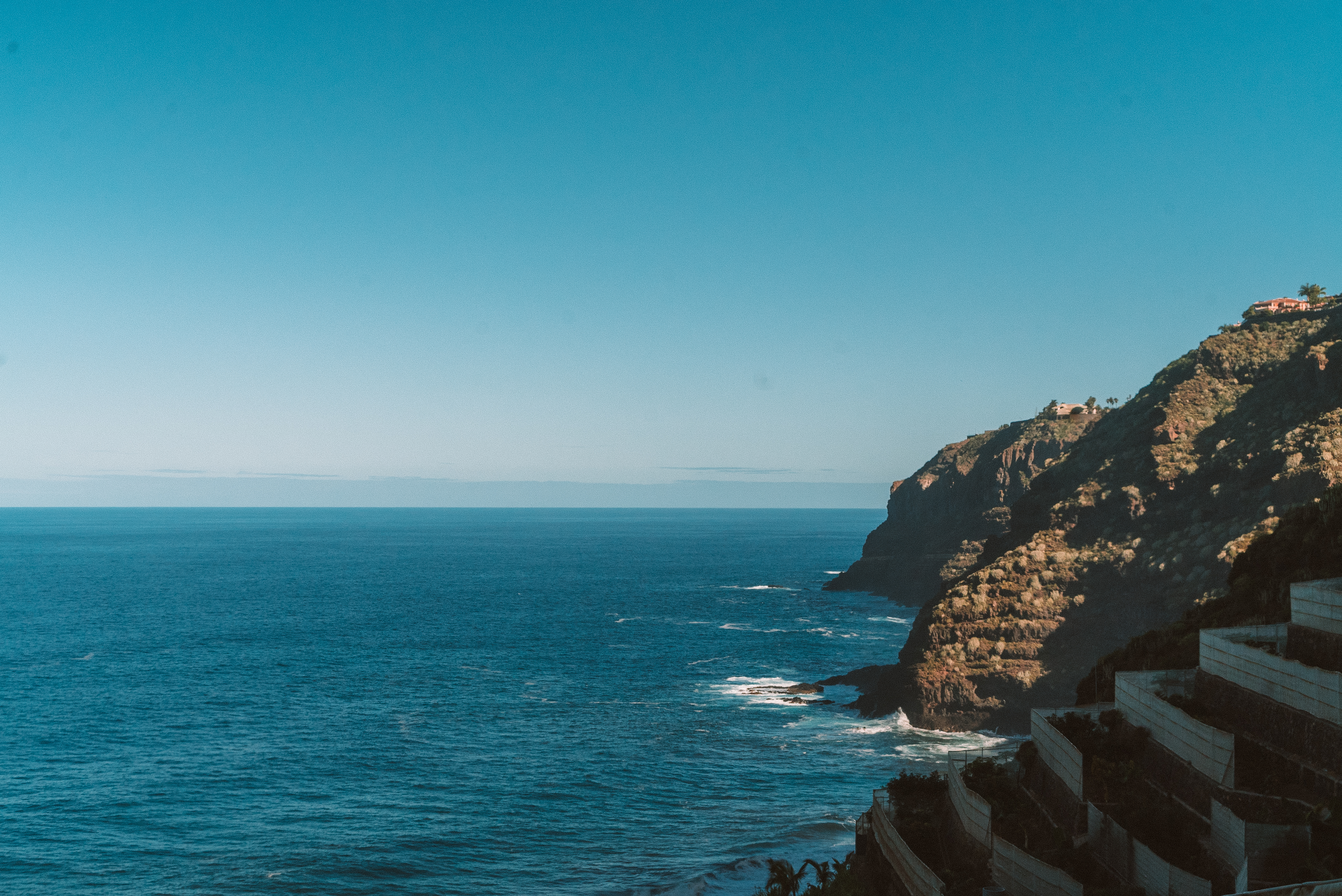 a cliff with a body of water and buildings