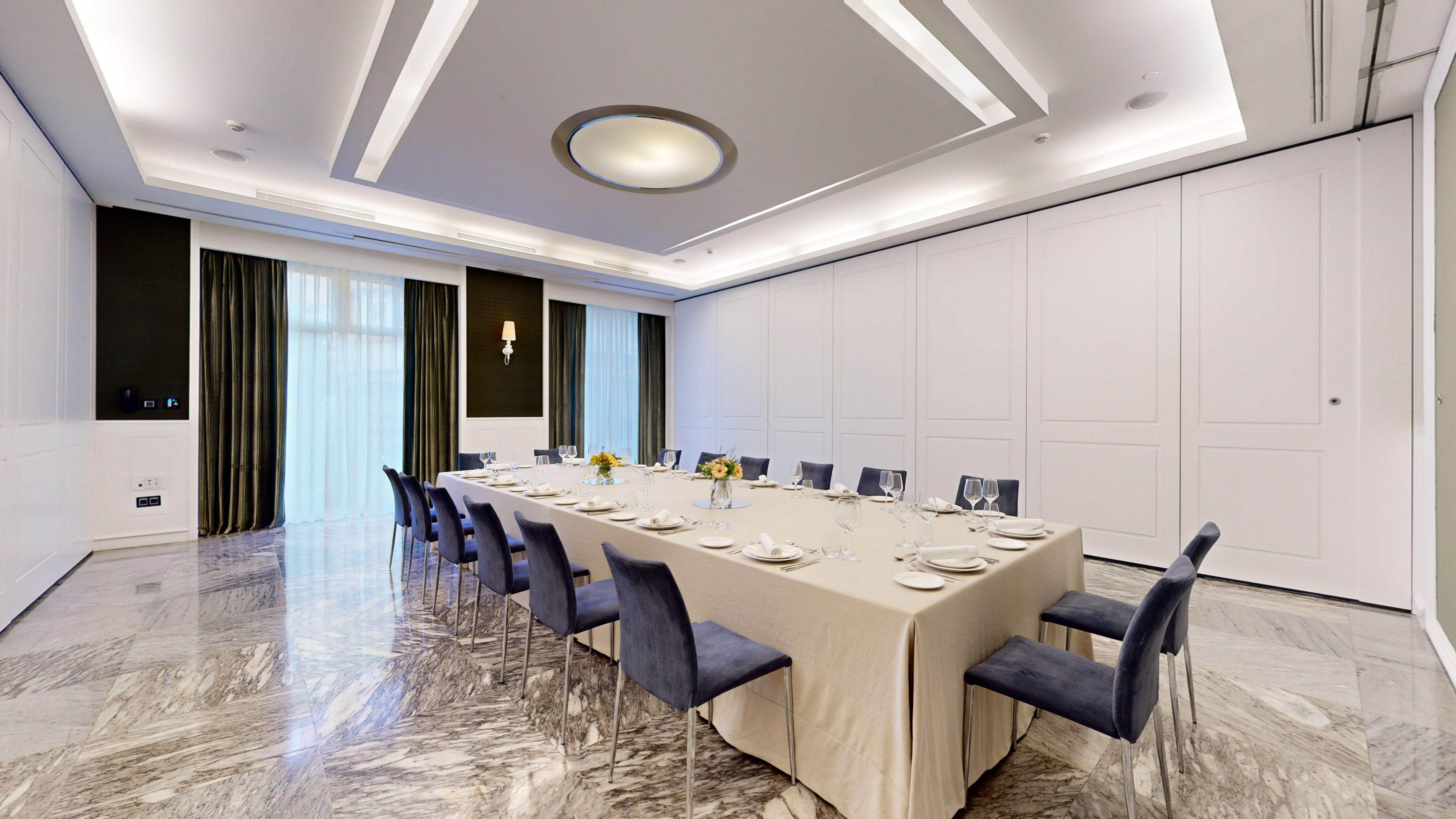 Elegant private dining room with formal table setting, velvet chairs, and marble floor.