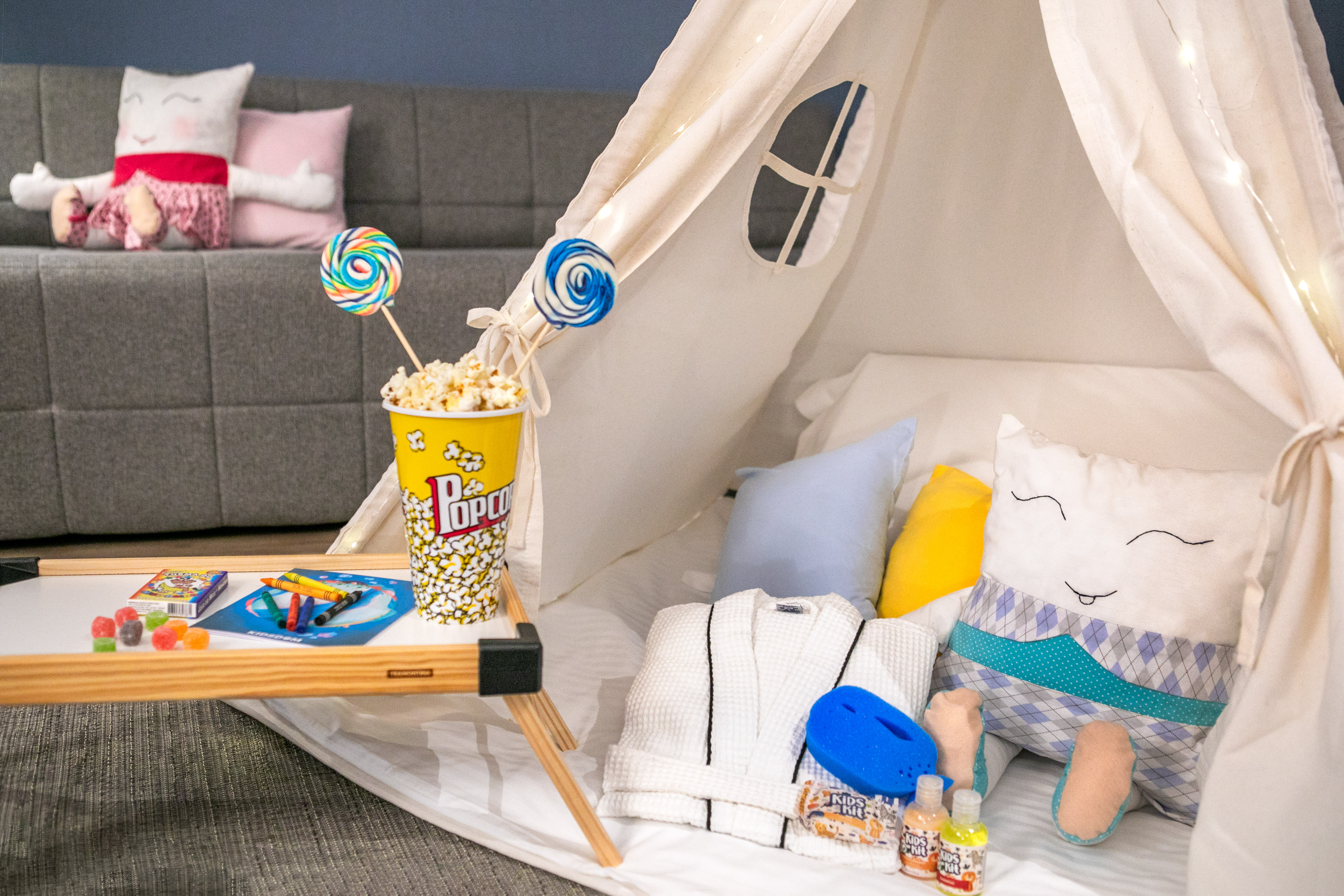 Kids' room teepee with popcorn, sweets, and crafts for a cozy stay.