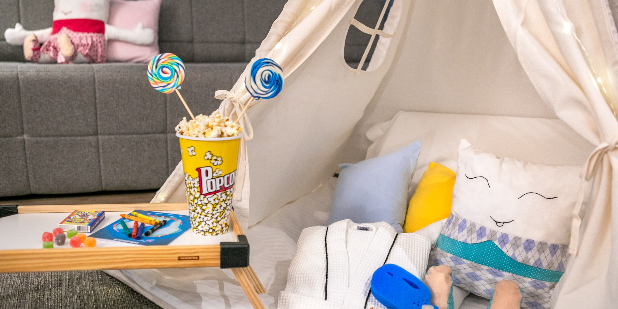 Kids' room teepee with popcorn, sweets, and crafts for a cozy stay.