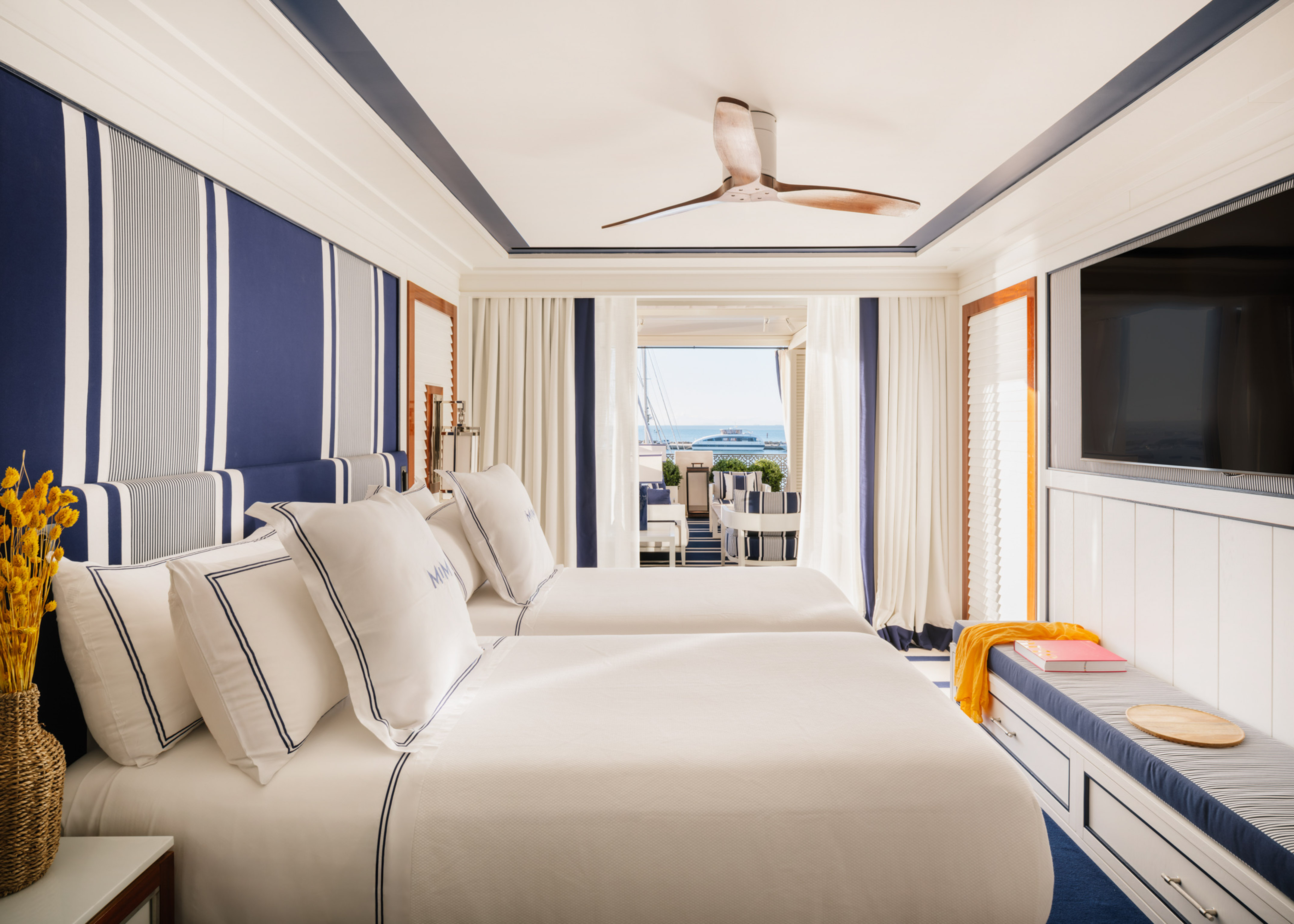Luxury yacht cabin with blue and white twin beds, ocean view.