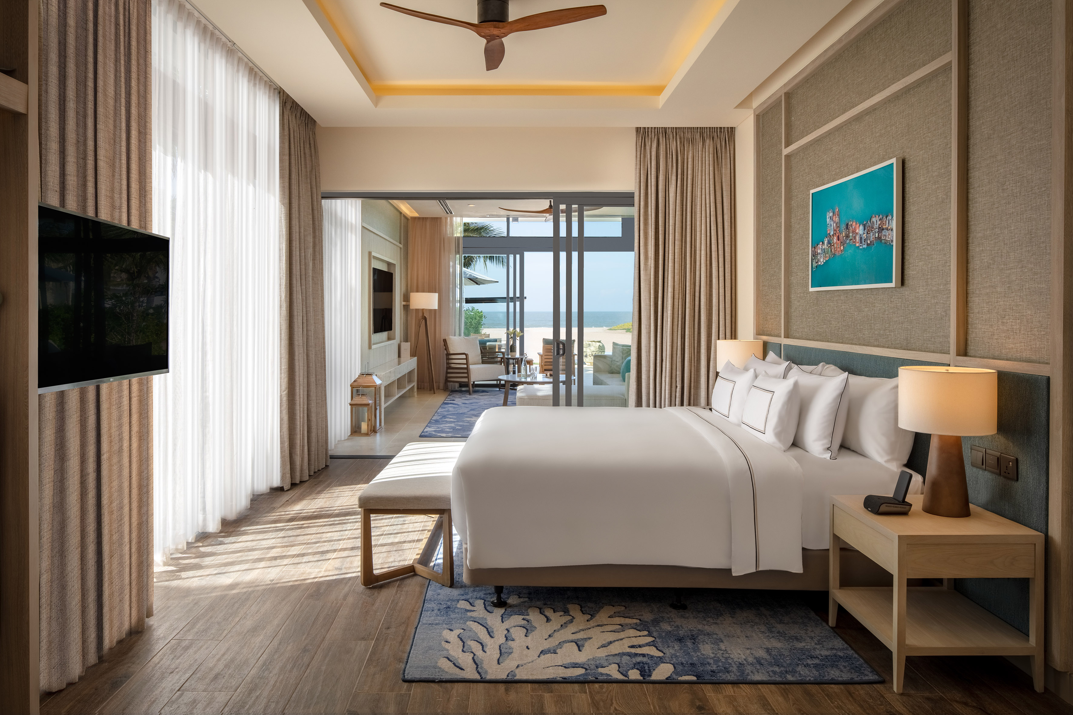 Stylish luxury hotel bedroom suite with ocean view, king bed, and private terrace.