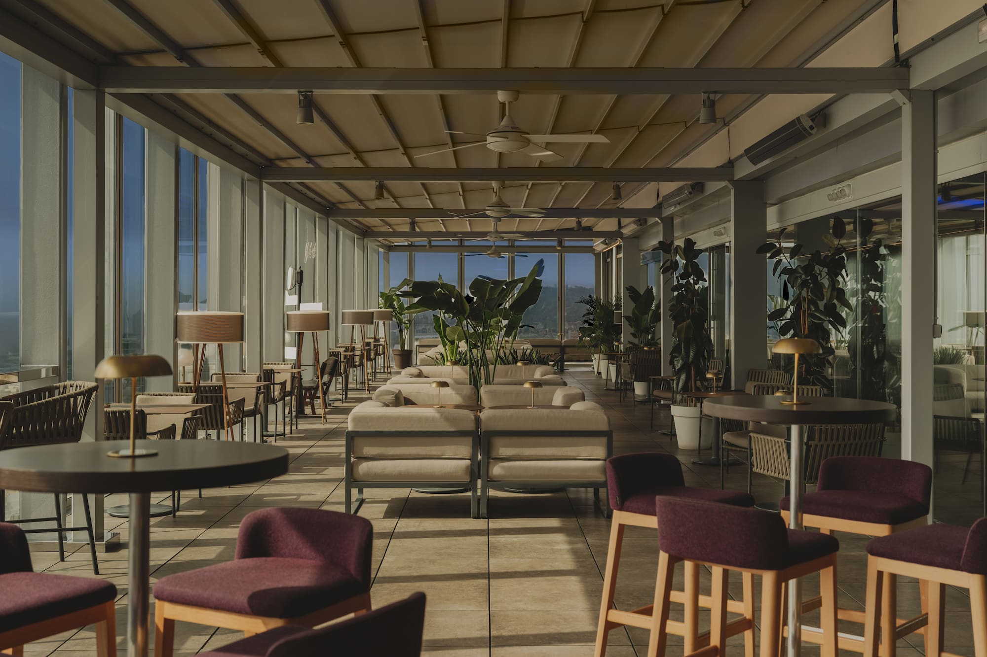 Terraza de restaurante moderna con sofás y vistas panorámicas.