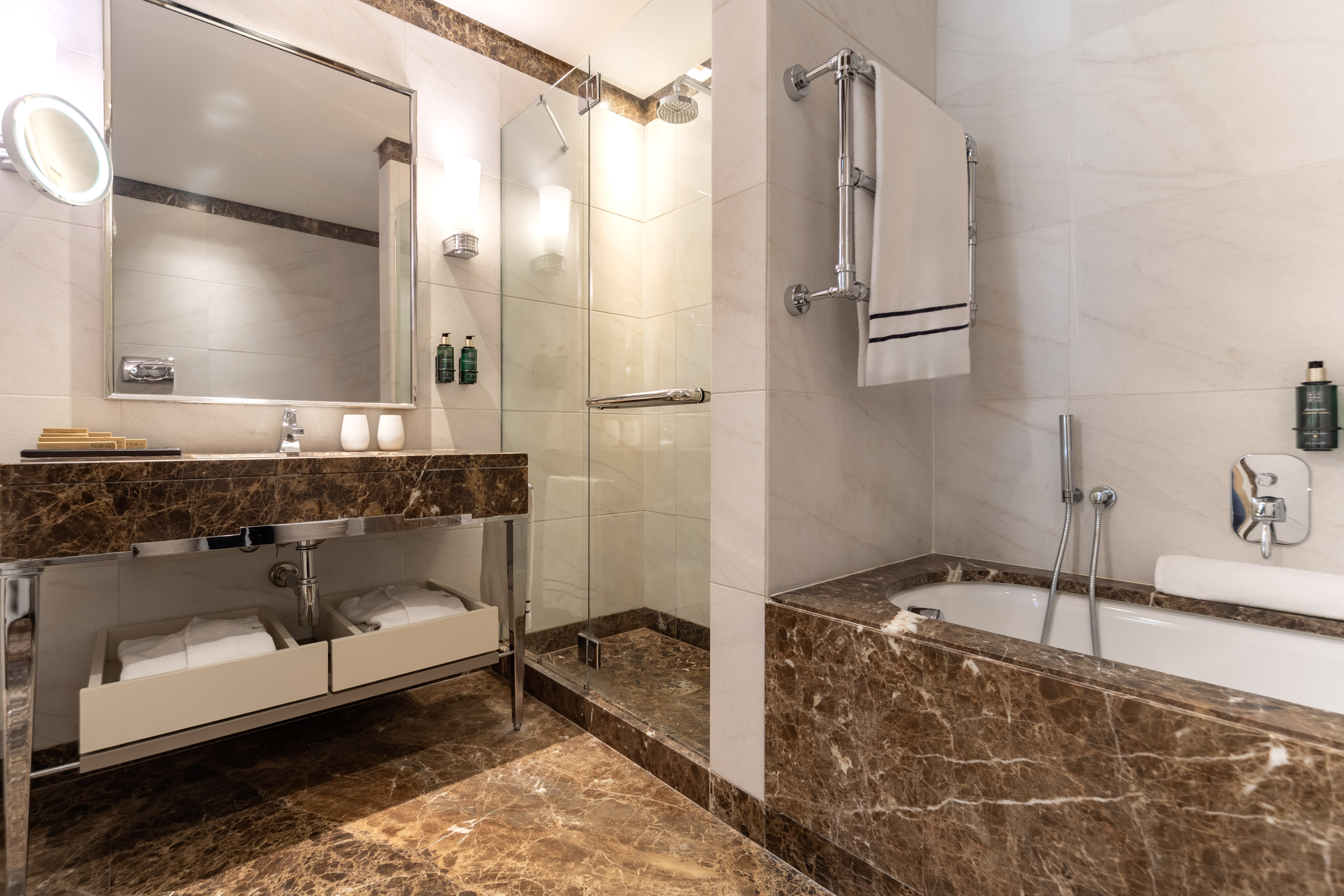 Luxury hotel bathroom with marble vanity, glass shower, and bathtub.