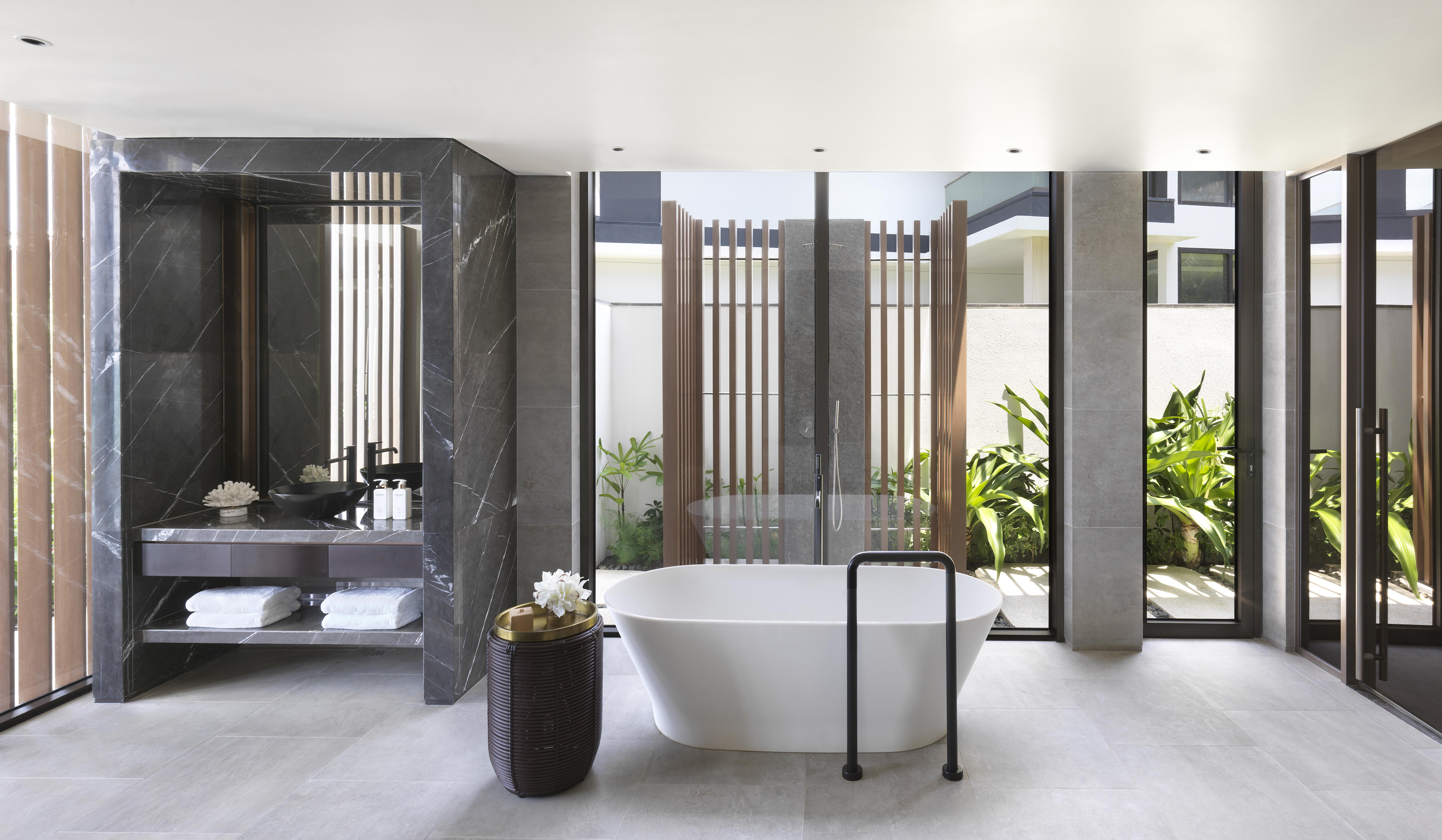 Modern luxury bathroom with freestanding tub, marble vanity, and lush garden view.