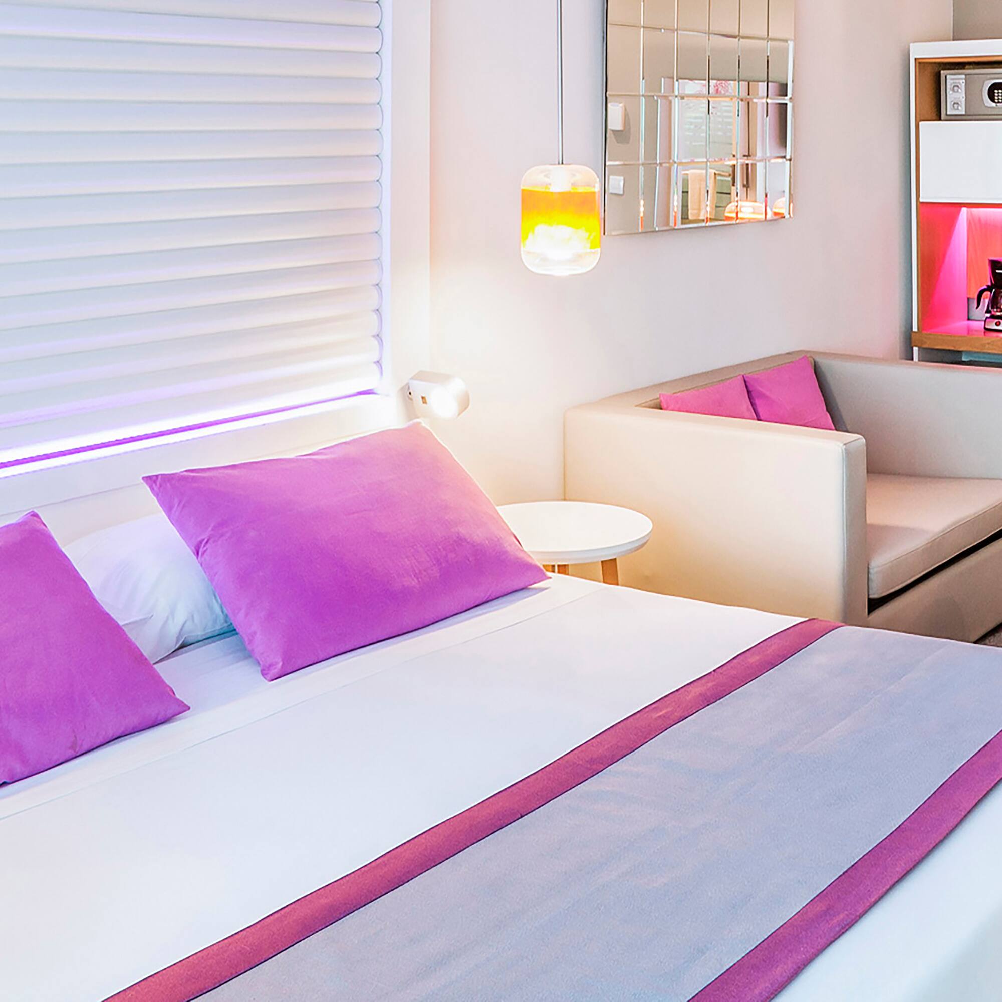 a bed with purple pillows and a couch in a room